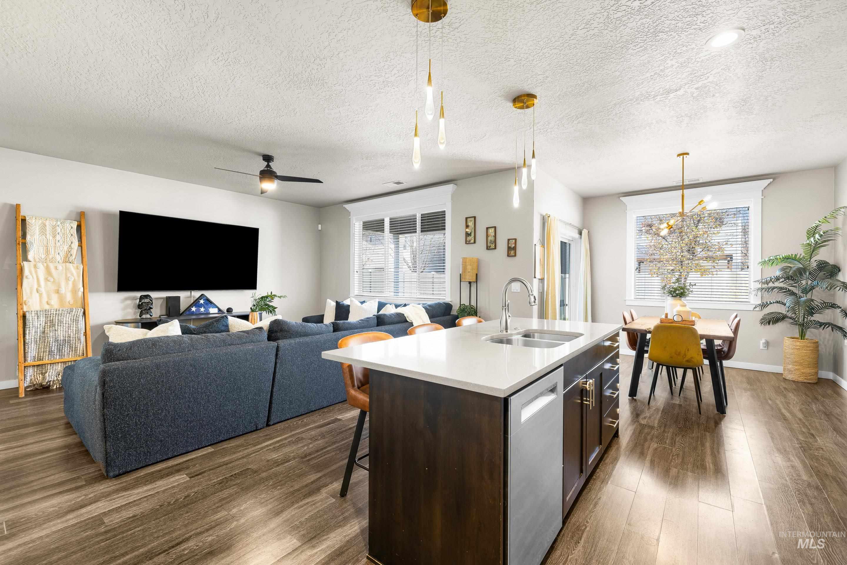 Kitchen featuring dark wood-style floors, decorative light fixtures, a kitchen breakfast bar, dark brown cabinets, and a textured ceiling