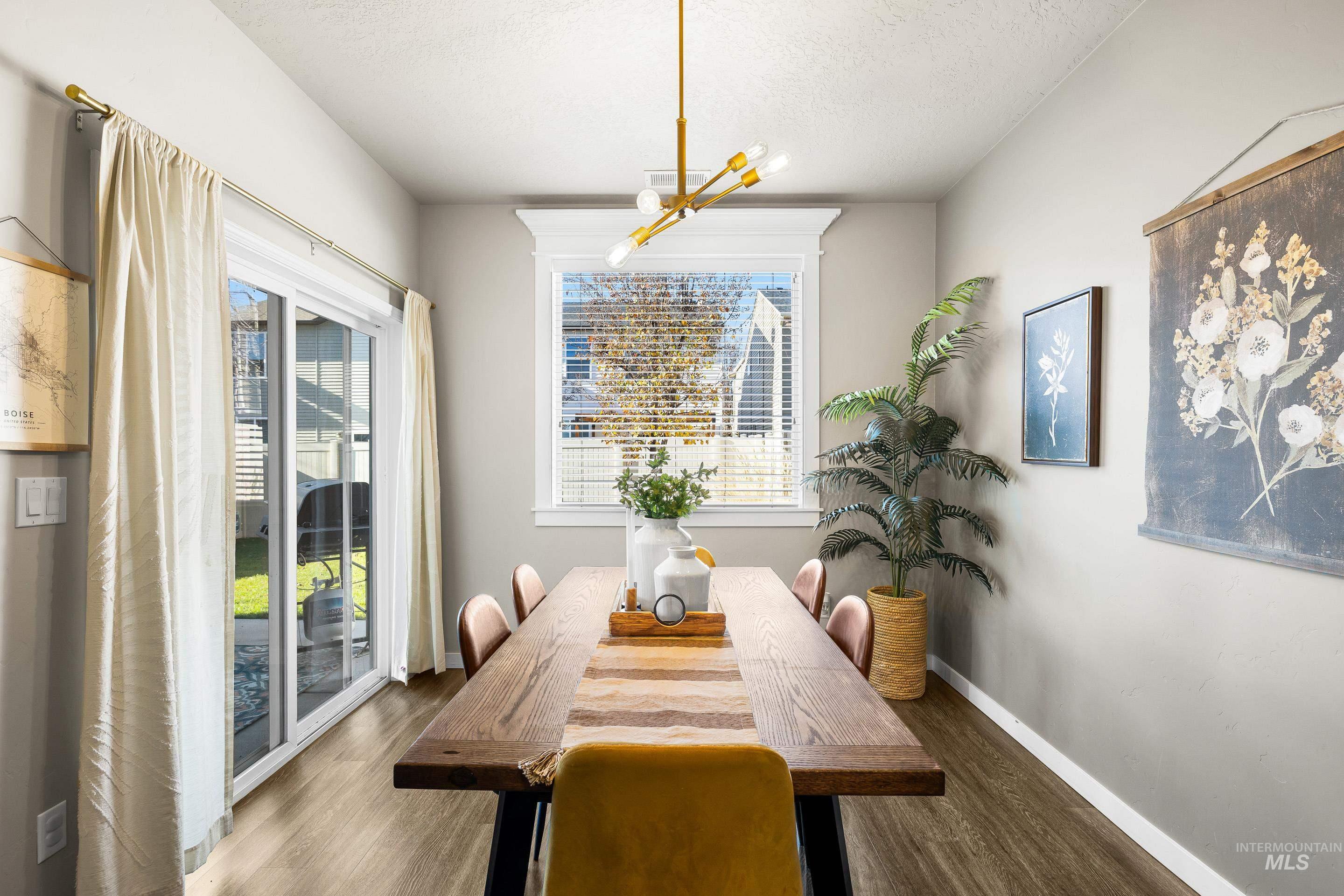 Dining space with wood finished floors, a textured ceiling, and a chandelier