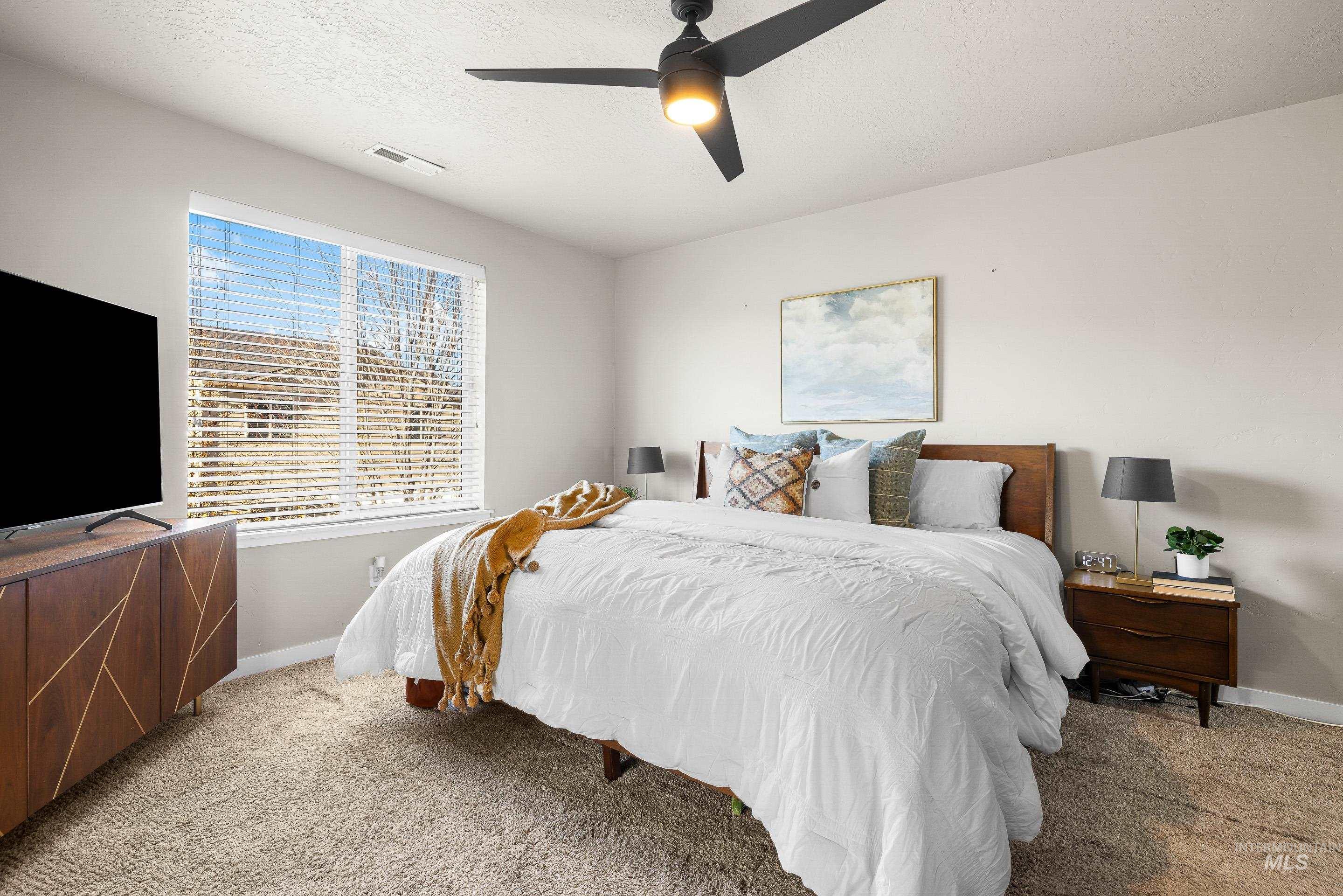 Bedroom featuring carpet flooring, a ceiling fan, and a textured ceiling