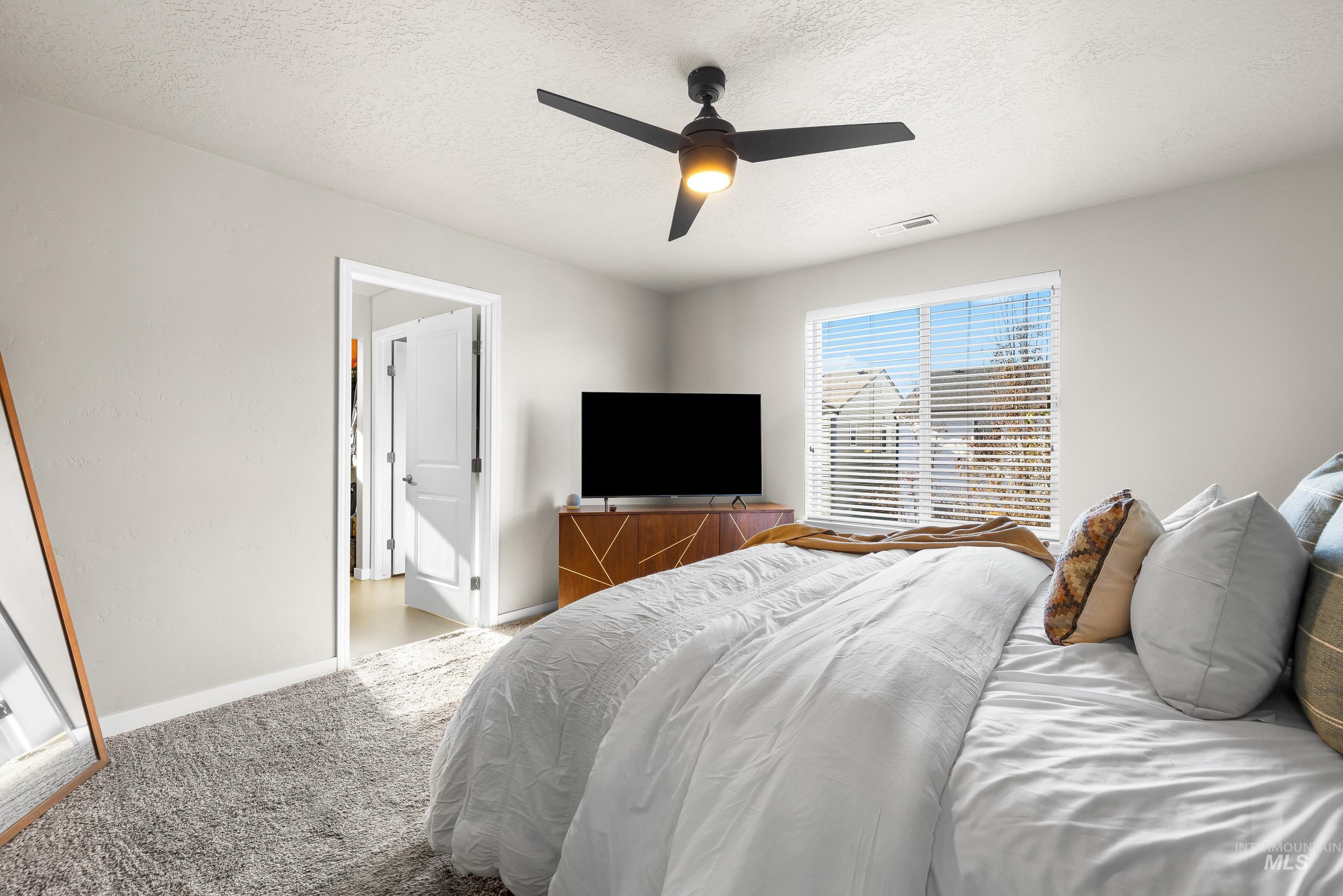 Bedroom featuring carpet flooring, a textured ceiling, and a ceiling fan