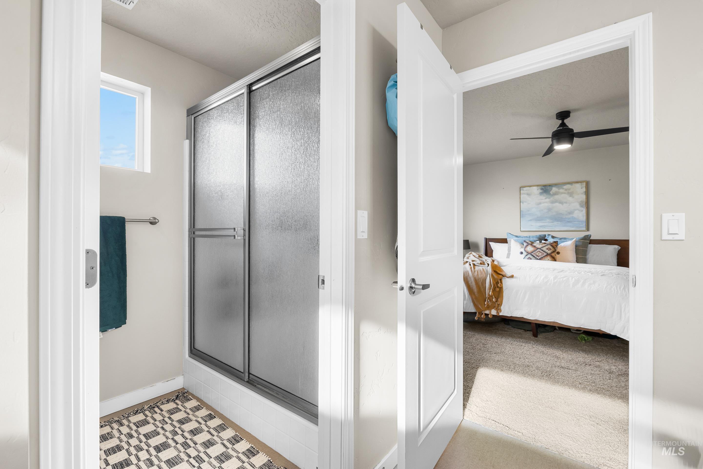 Ensuite bathroom featuring a shower stall, ceiling fan, tile patterned floors, a textured ceiling, and carpet