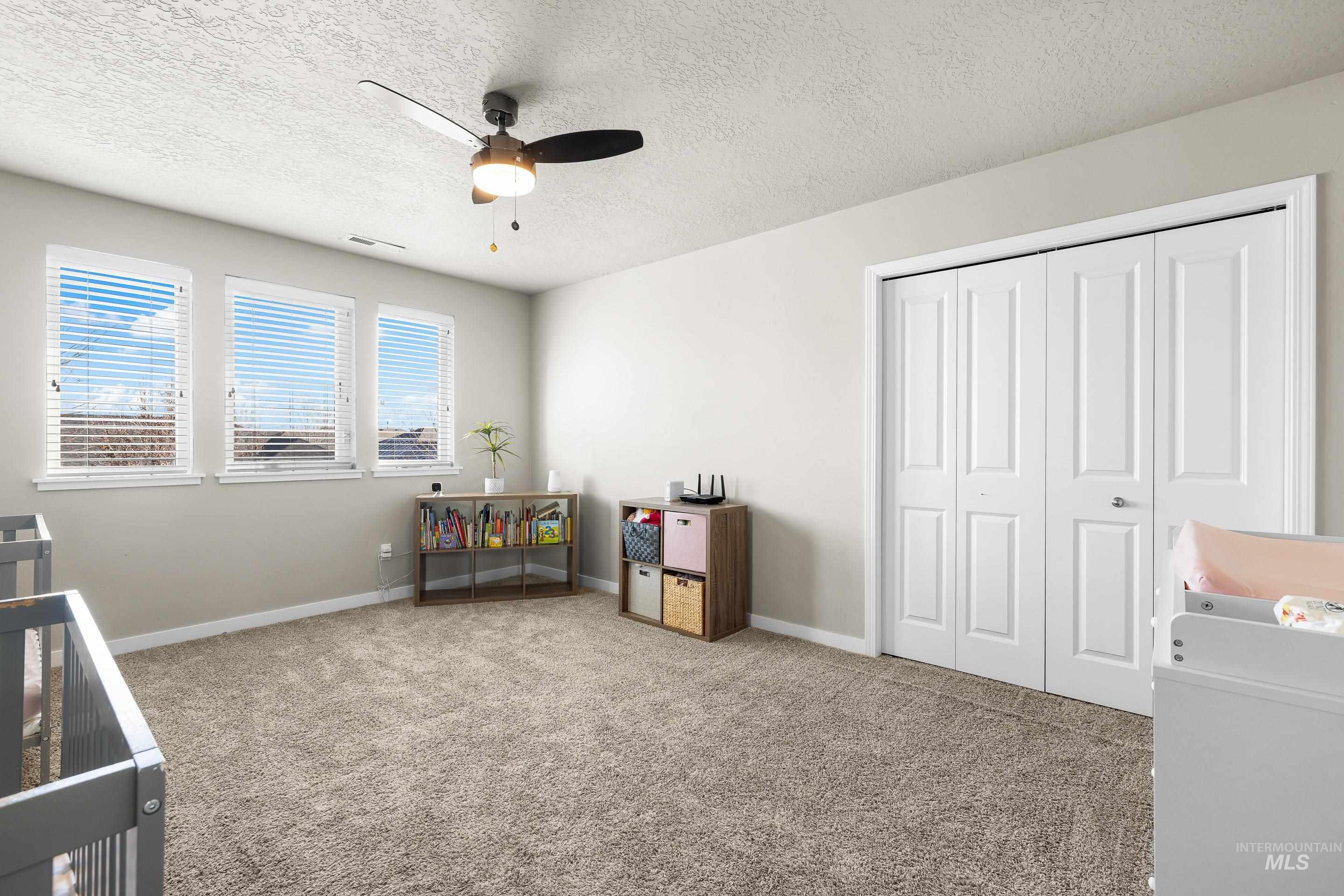 Carpeted bedroom with a textured ceiling, a closet, and ceiling fan