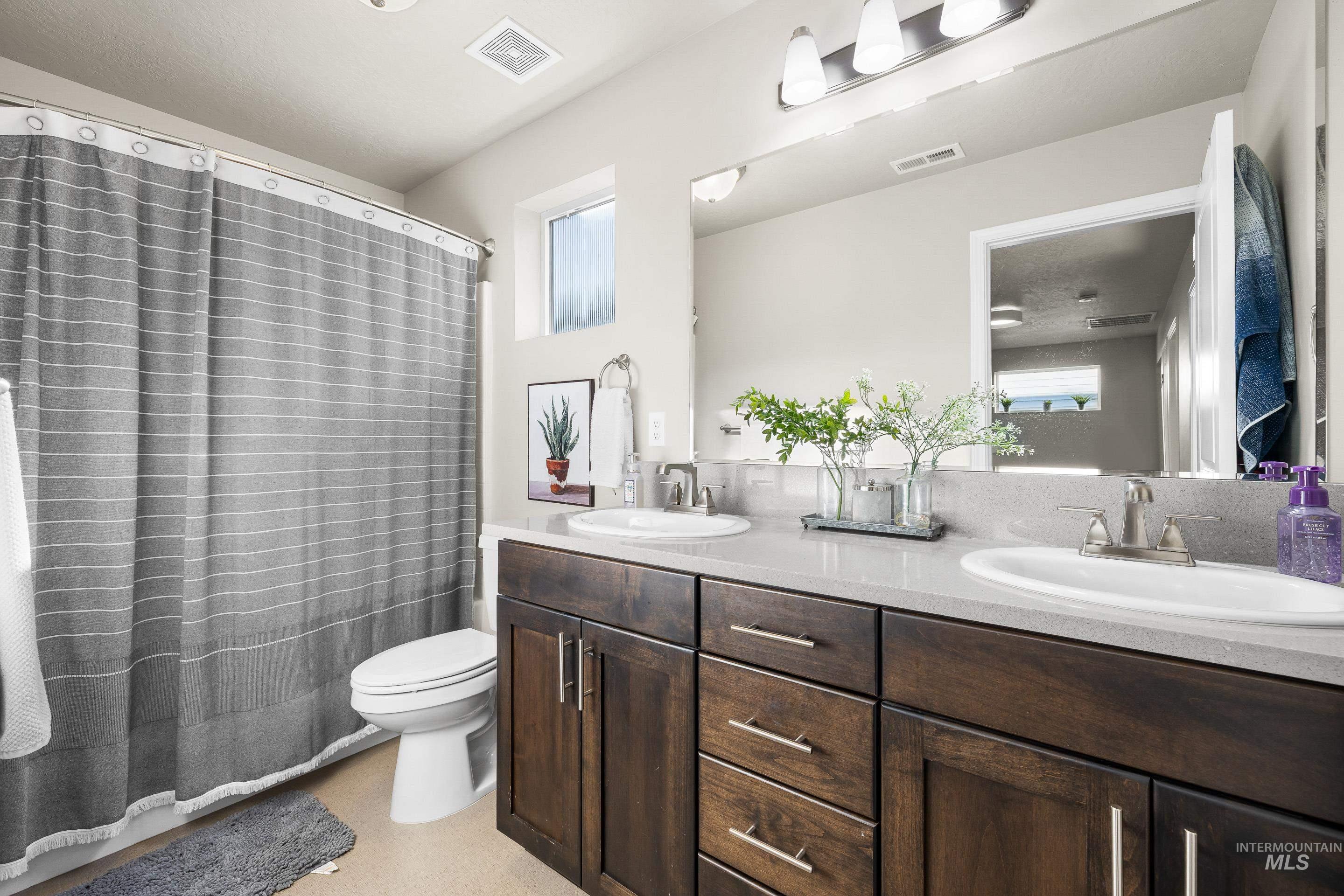Bathroom with double vanity and curtained shower