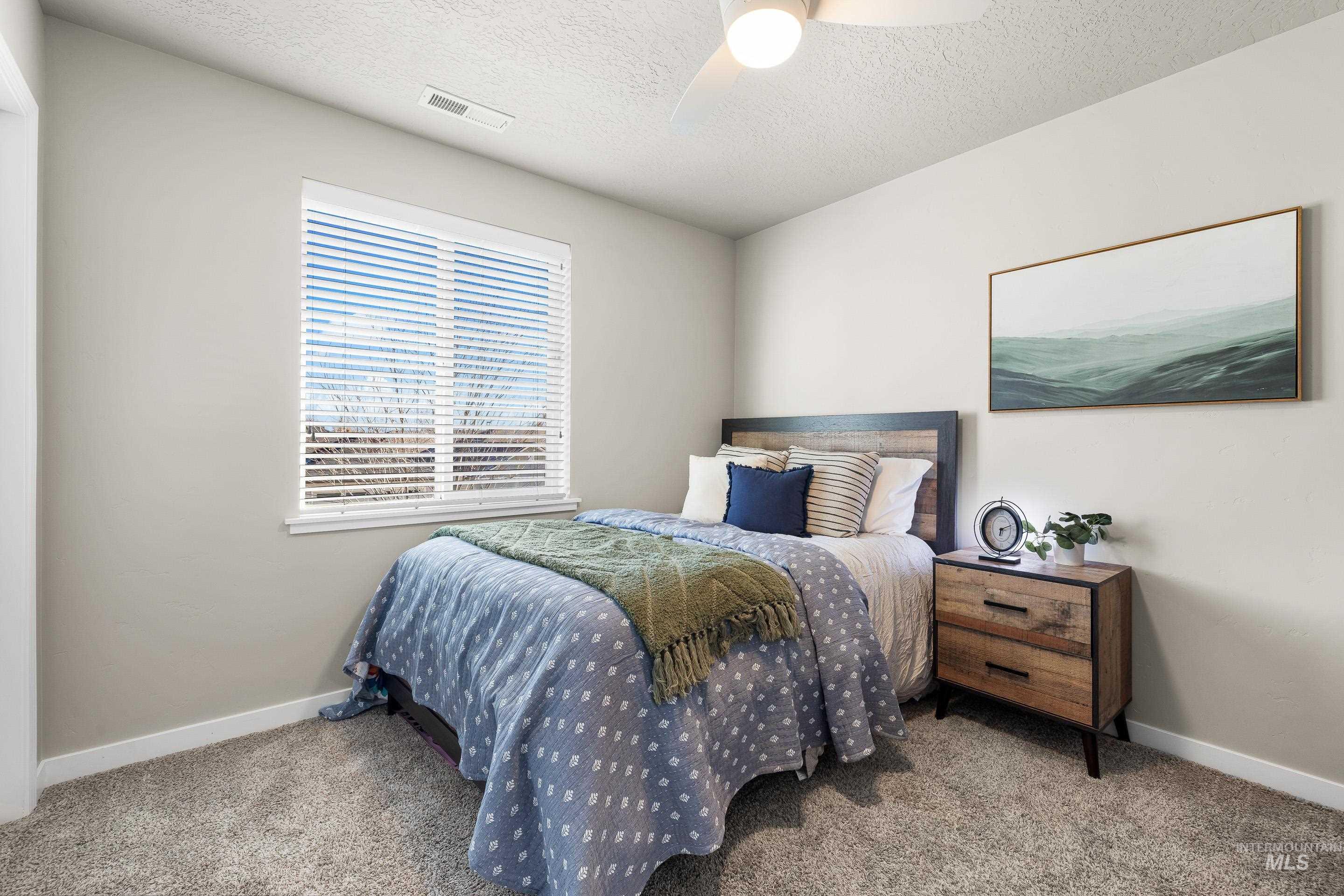 Bedroom with light carpet, a textured ceiling, and a ceiling fan