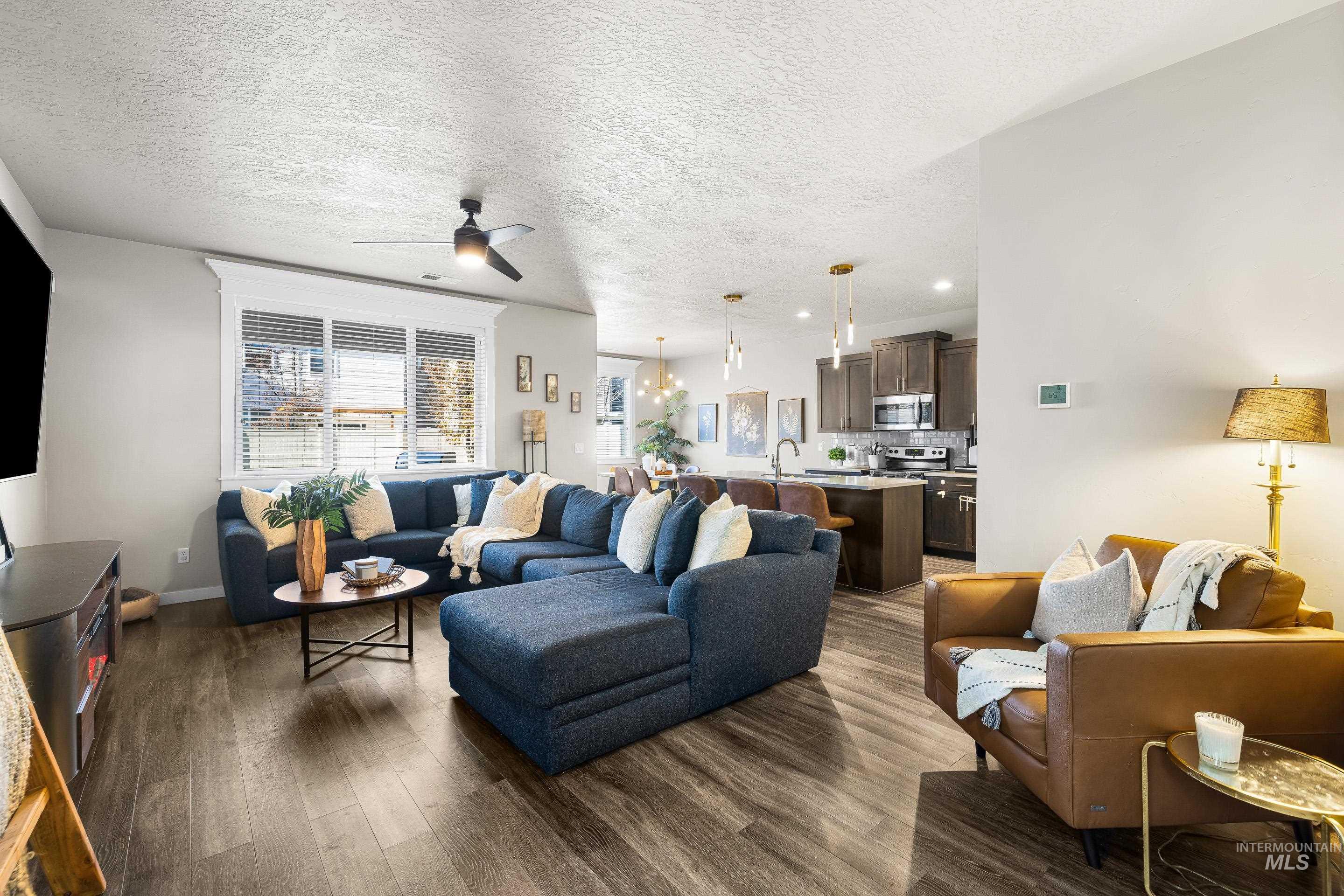Living area featuring a textured ceiling, a ceiling fan, dark wood-style flooring, and recessed lighting
