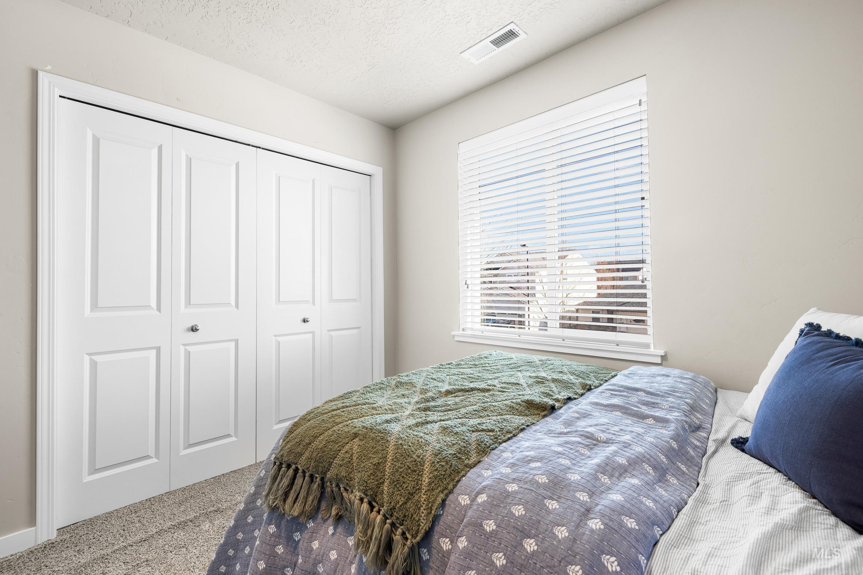Bedroom featuring carpet flooring, a textured ceiling, and a closet