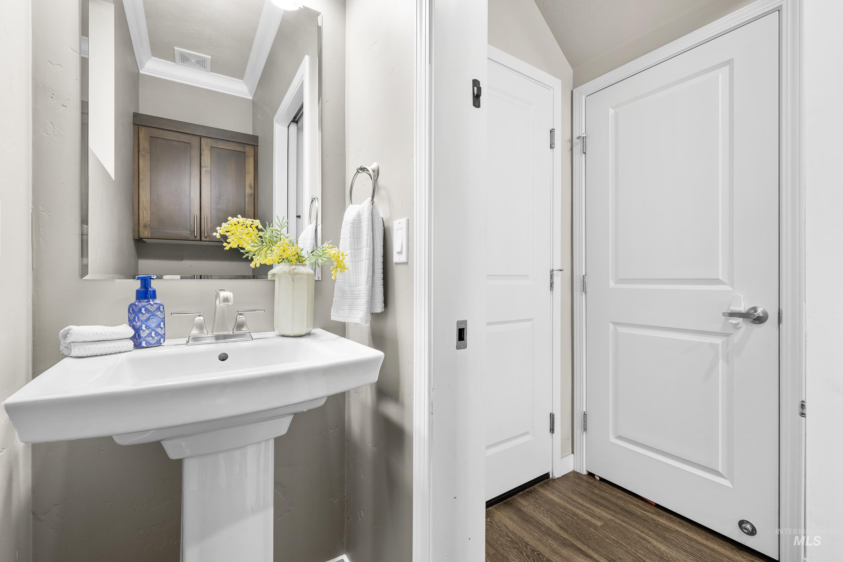 Bathroom featuring dark wood finished floors and ornamental molding