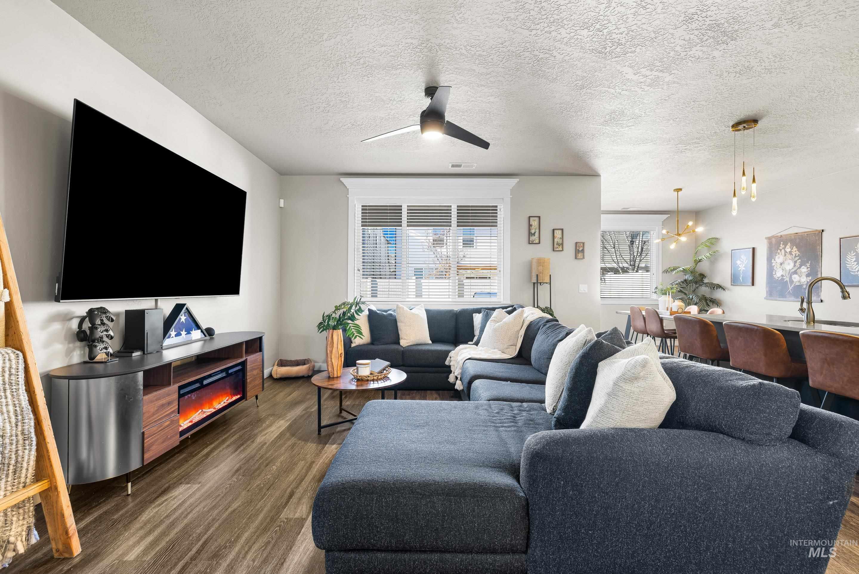 Living area featuring wood finished floors, a textured ceiling, and ceiling fan