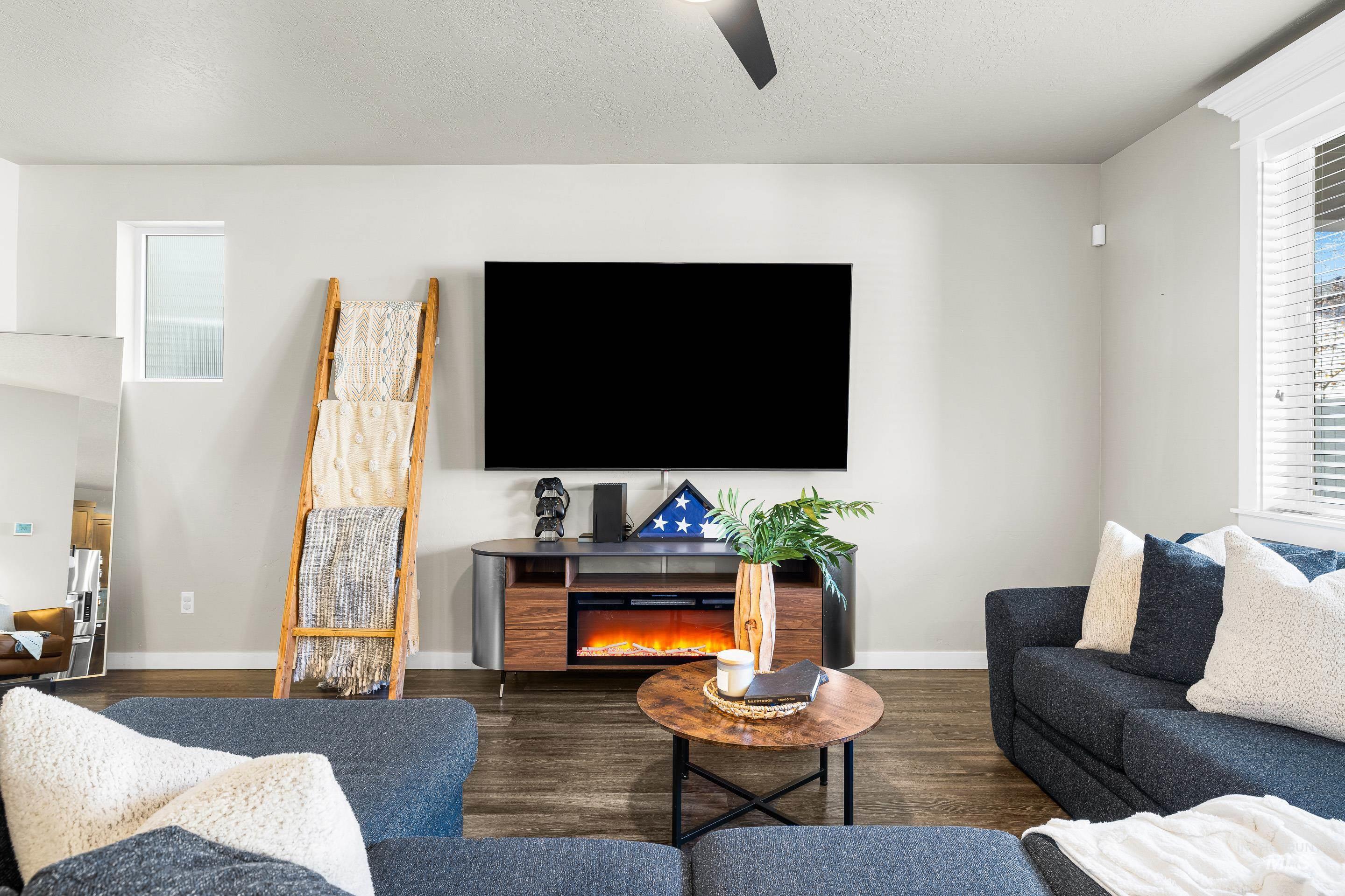 Living area with wood finished floors, a textured ceiling, and a lit fireplace