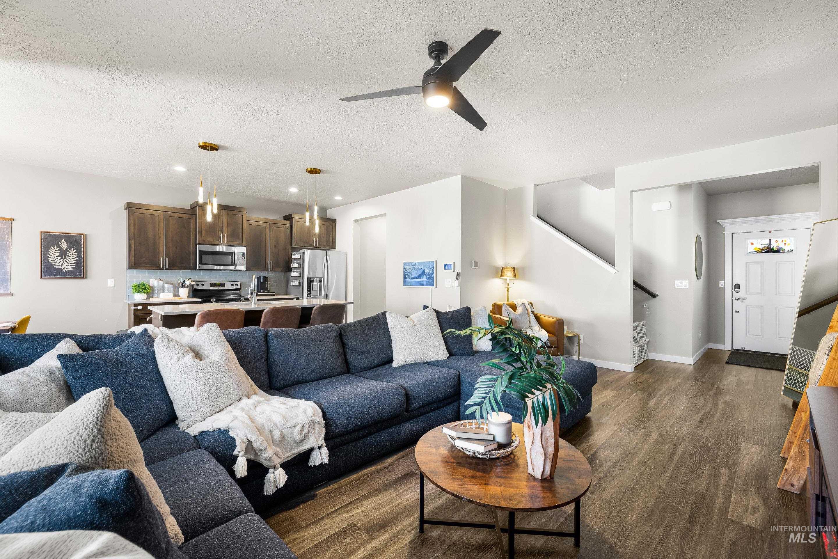 Living area with stairway, dark wood-style flooring, a textured ceiling, and a ceiling fan