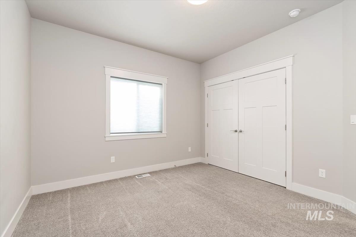 Unfurnished bedroom with light colored carpet and a closet
