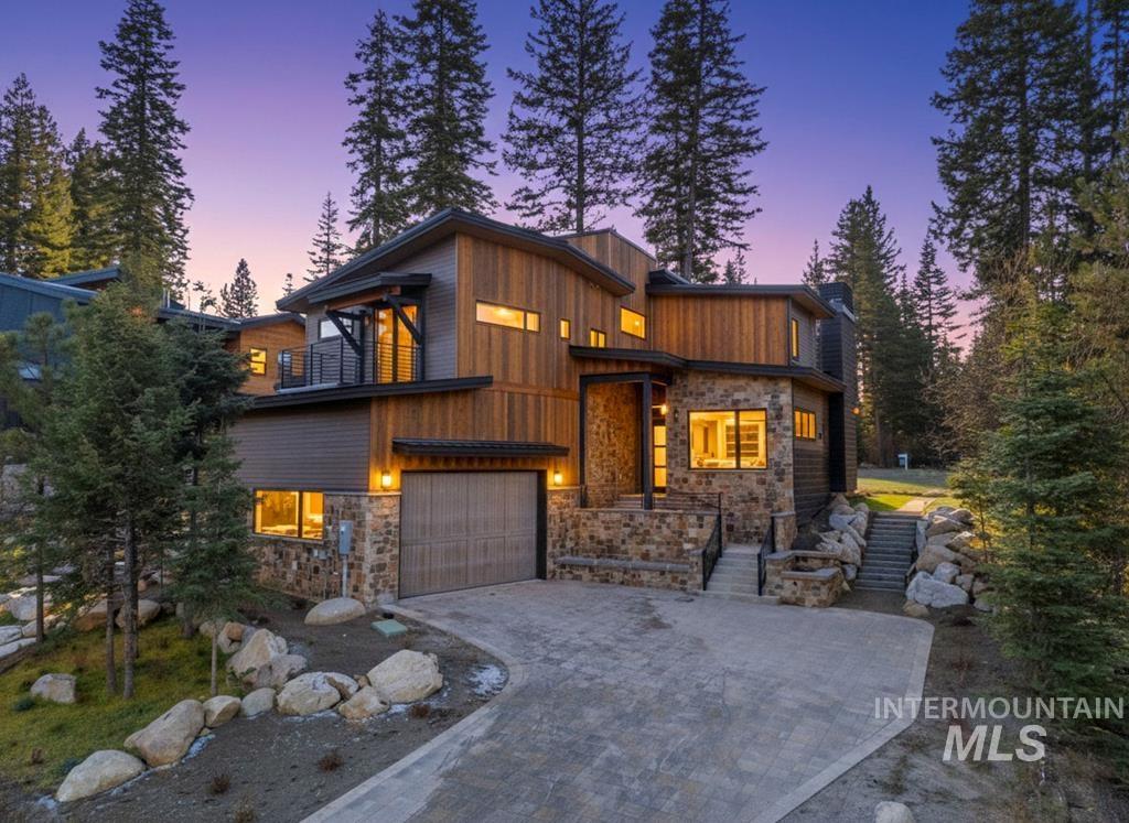 Contemporary home with stone siding, decorative driveway, and an attached garage