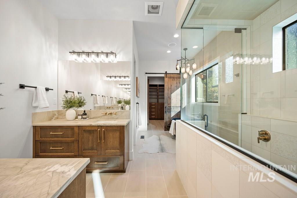 Primary Bathroom featuring a stall shower, vanity, a walk in closet, light tile patterned floors, and recessed lighting