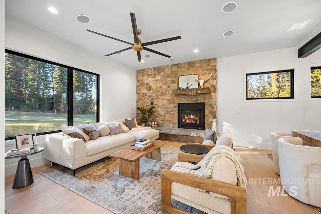 Living area featuring a fireplace, a ceiling fan, light wood-style floors, healthy amount of natural light, and recessed lighting