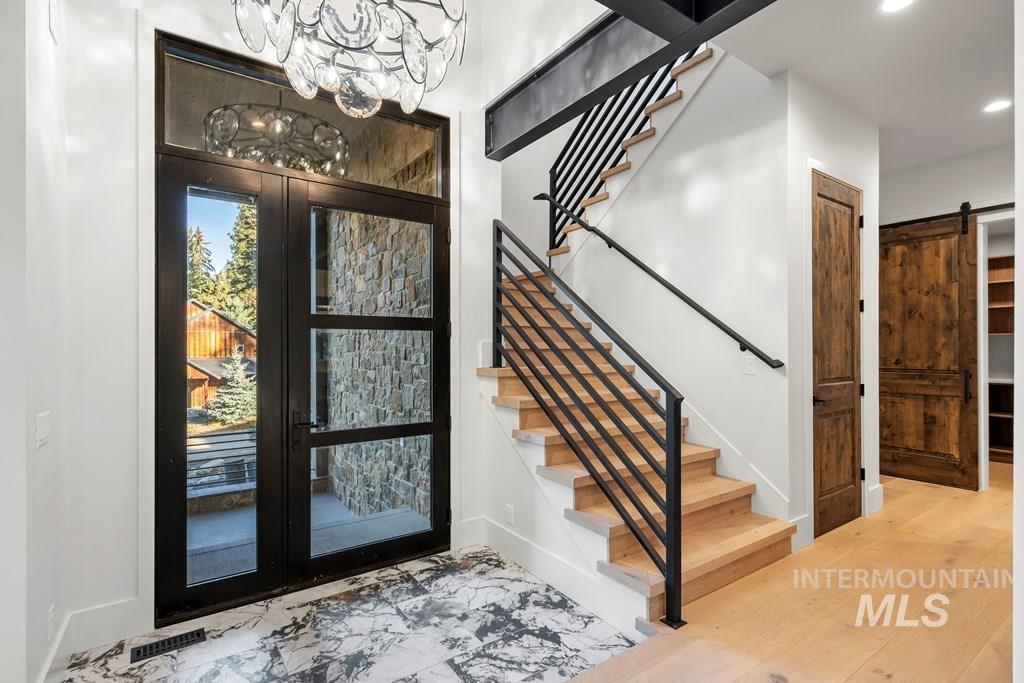 Entrance foyer featuring a barn door, stairs, recessed lighting, french doors, and marble finish floors