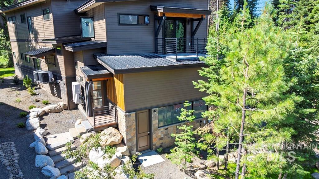 Modern home with stone siding, a metal roof, and a balcony