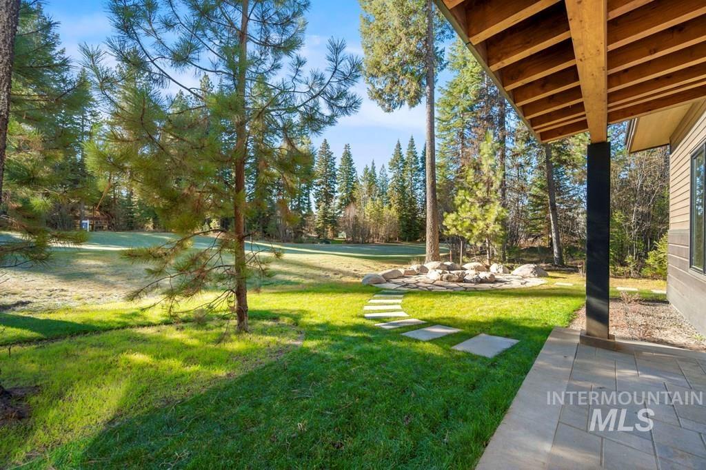 View of grassy yard with a patio area and view of wooded area