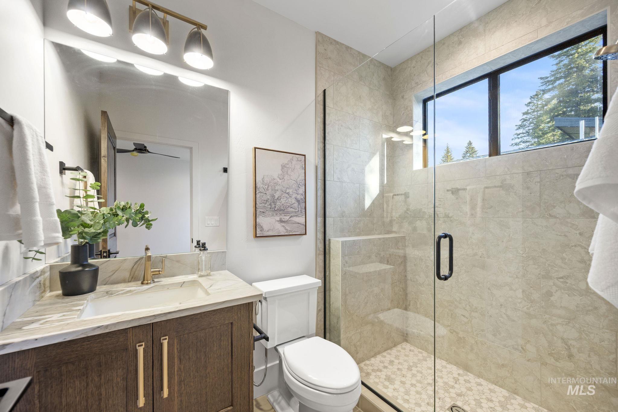 Bathroom featuring a stall shower, vanity, and ceiling fan