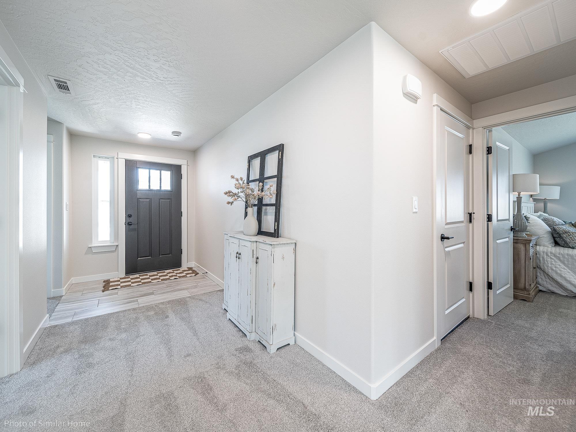 Foyer entrance with light carpet and a textured ceiling