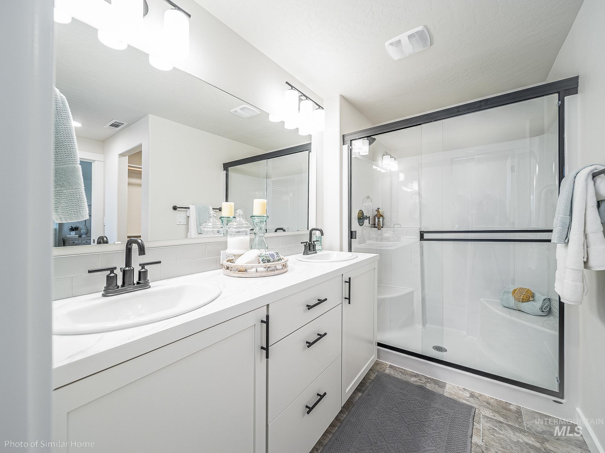Full bath featuring shower, dual vanities, his and hers closets