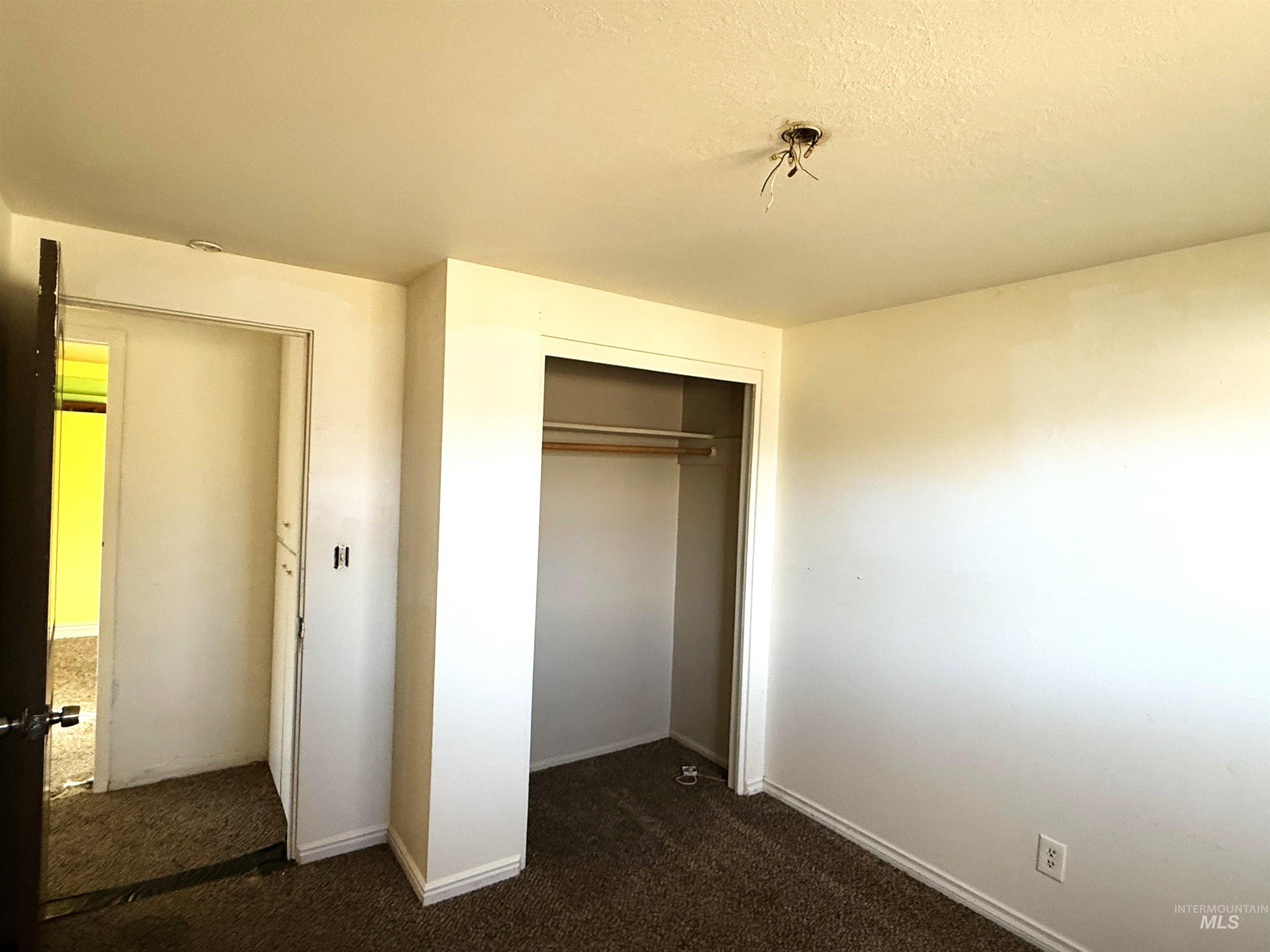 Unfurnished bedroom featuring dark carpet, a closet, and a textured ceiling