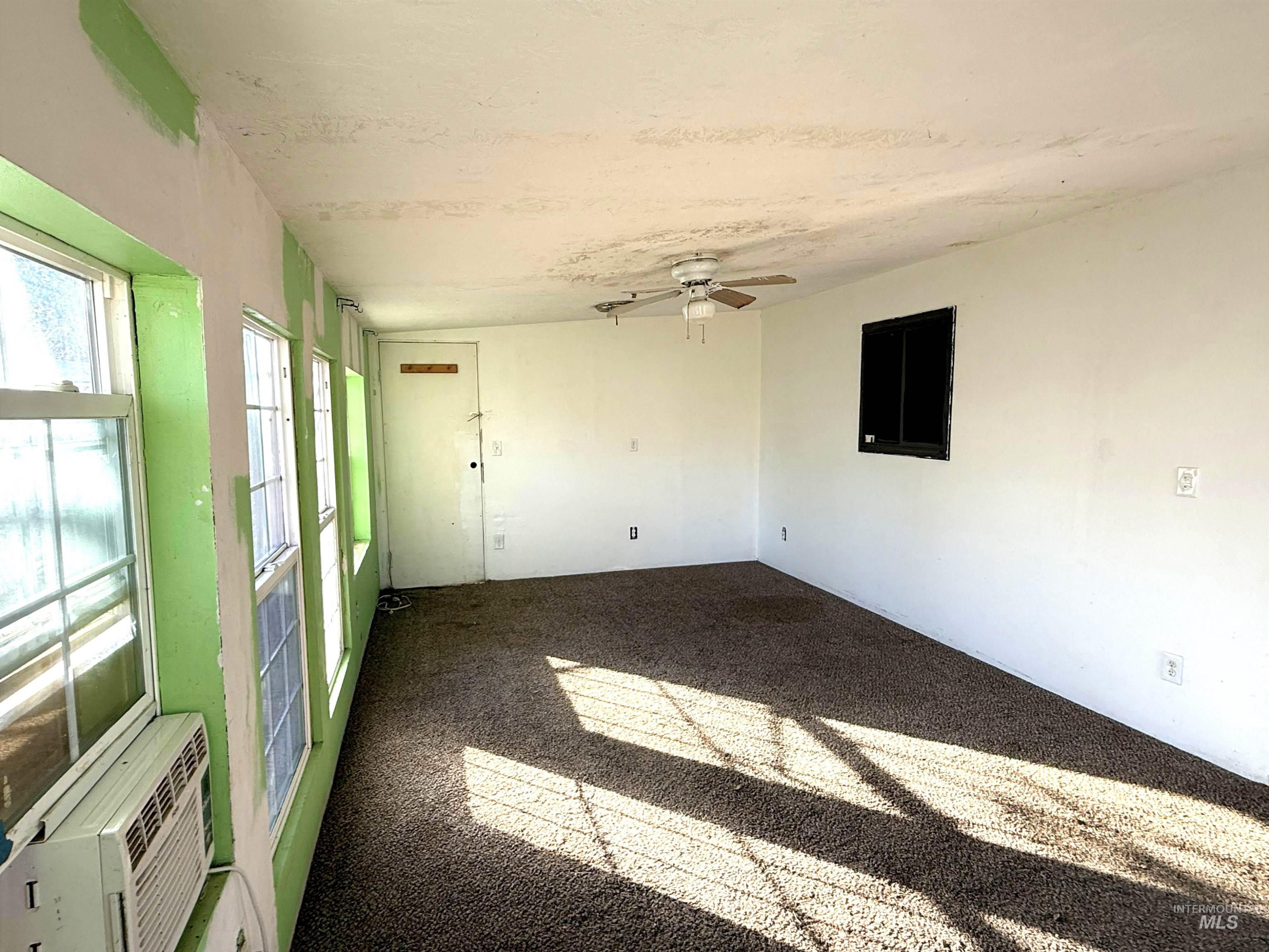 Empty room with carpet floors, ceiling fan, and cooling unit