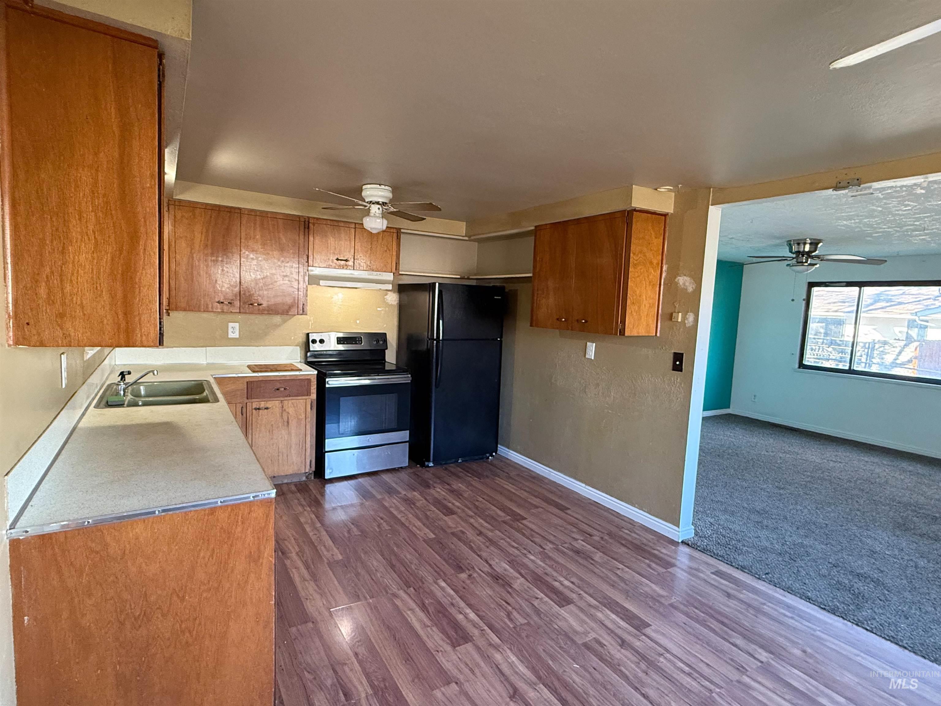 Kitchen with a ceiling fan, stainless steel electric range, light countertops, and freestanding refrigerator