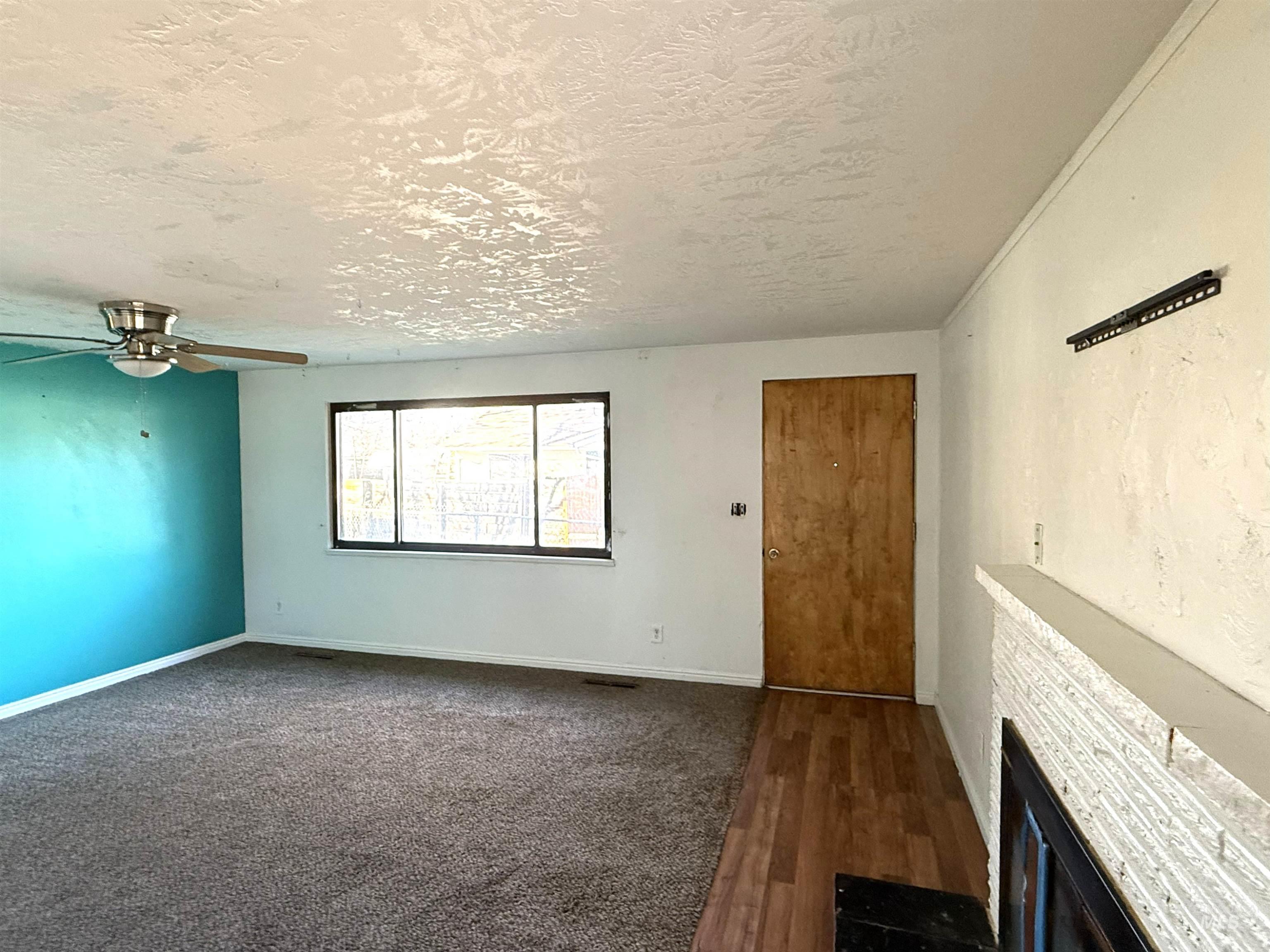 Unfurnished living room featuring a textured ceiling, dark wood-type flooring, ceiling fan, and a fireplace