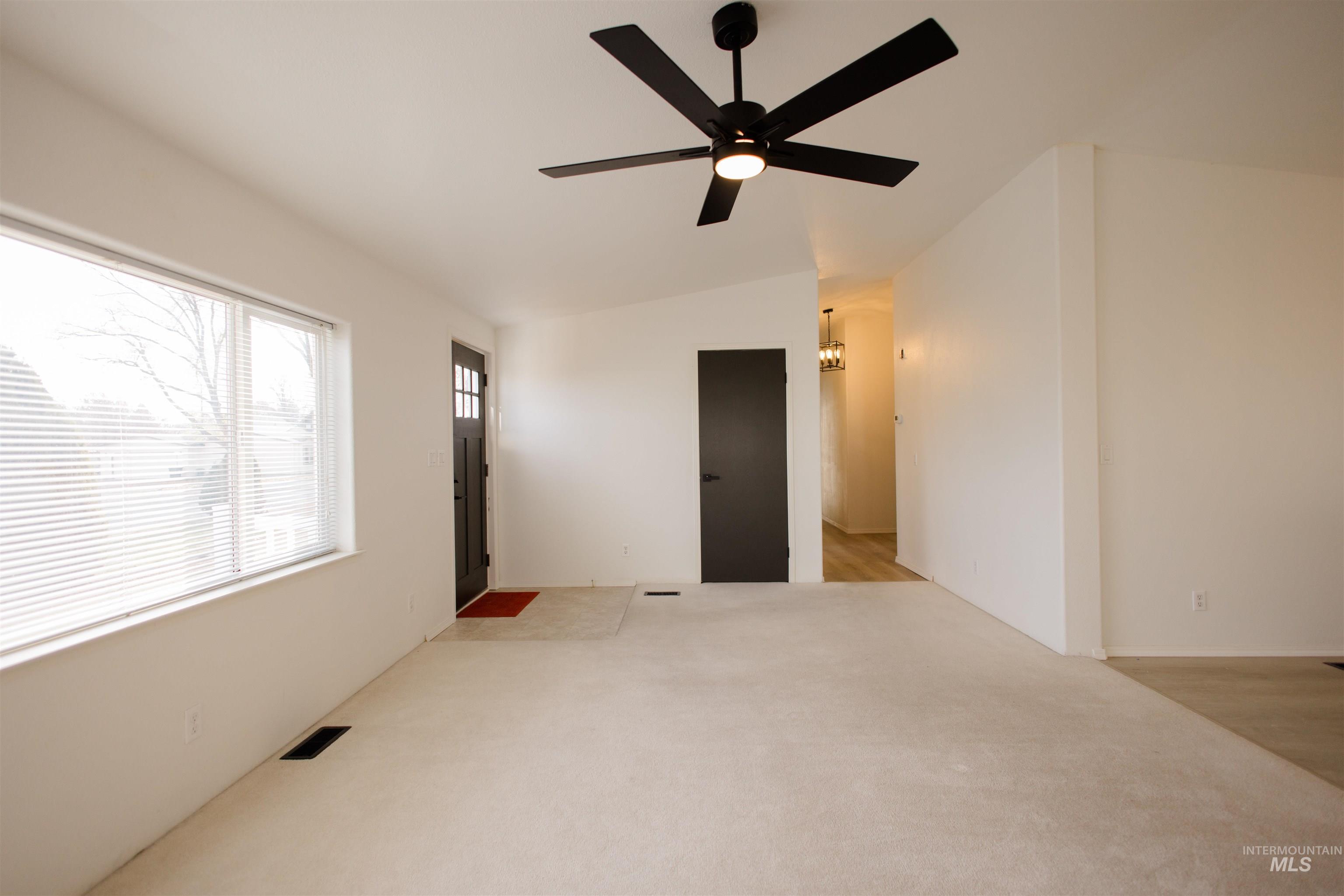 Unfurnished room with vaulted ceiling, a ceiling fan, and light carpet