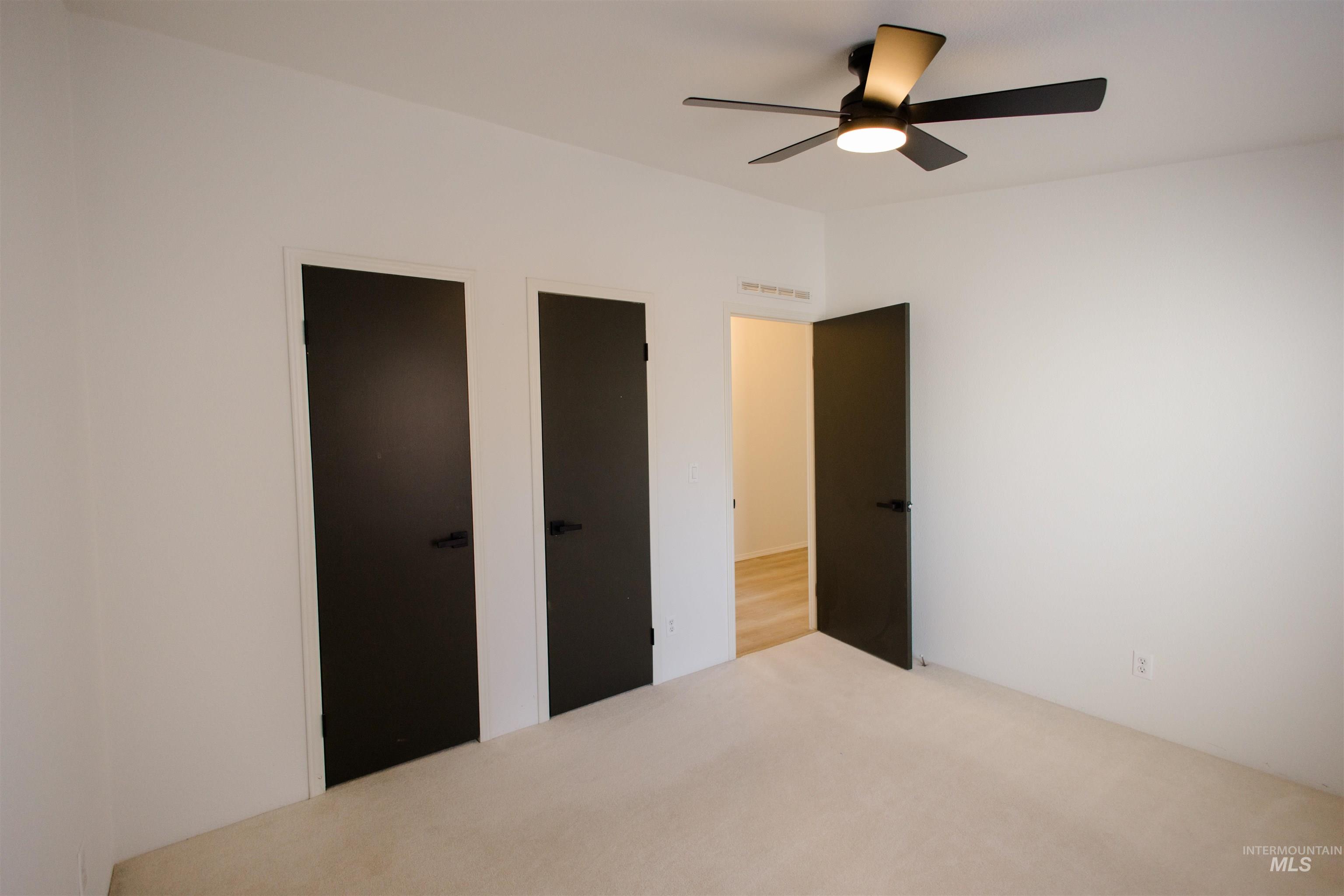 Unfurnished bedroom featuring a ceiling fan and two closets