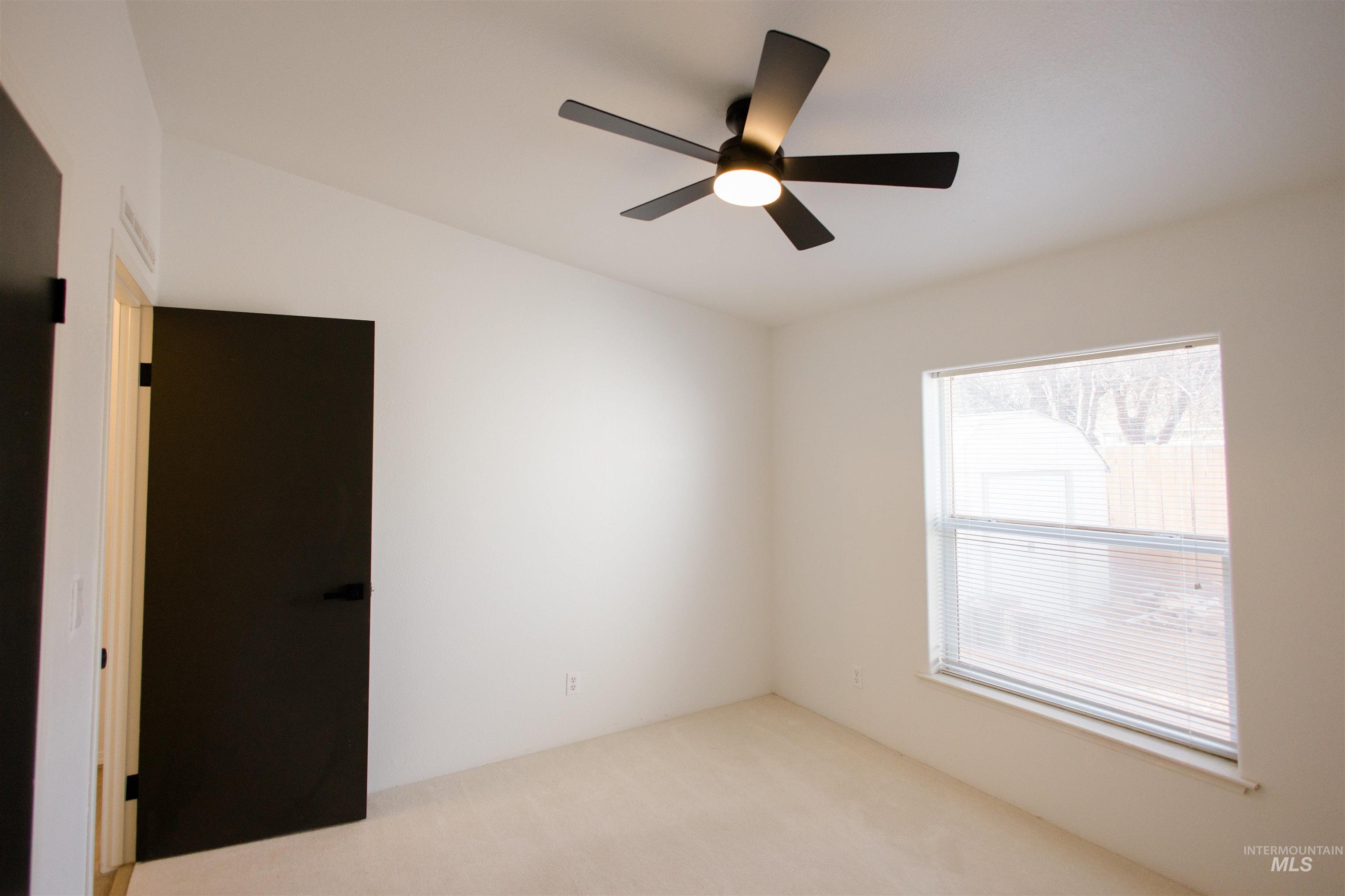 Carpeted empty room with a ceiling fan