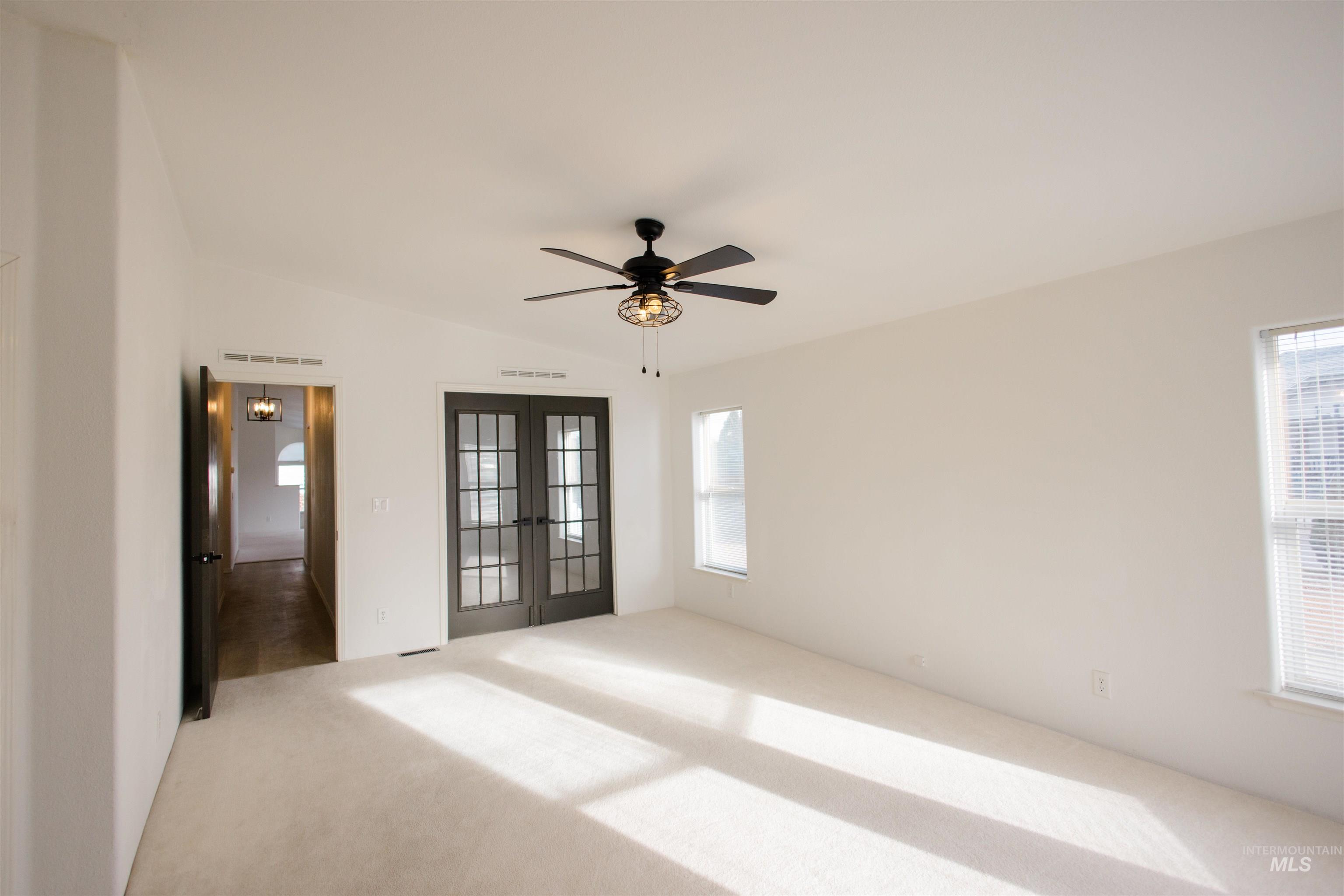 Empty room with french doors, a ceiling fan, vaulted ceiling, and carpet