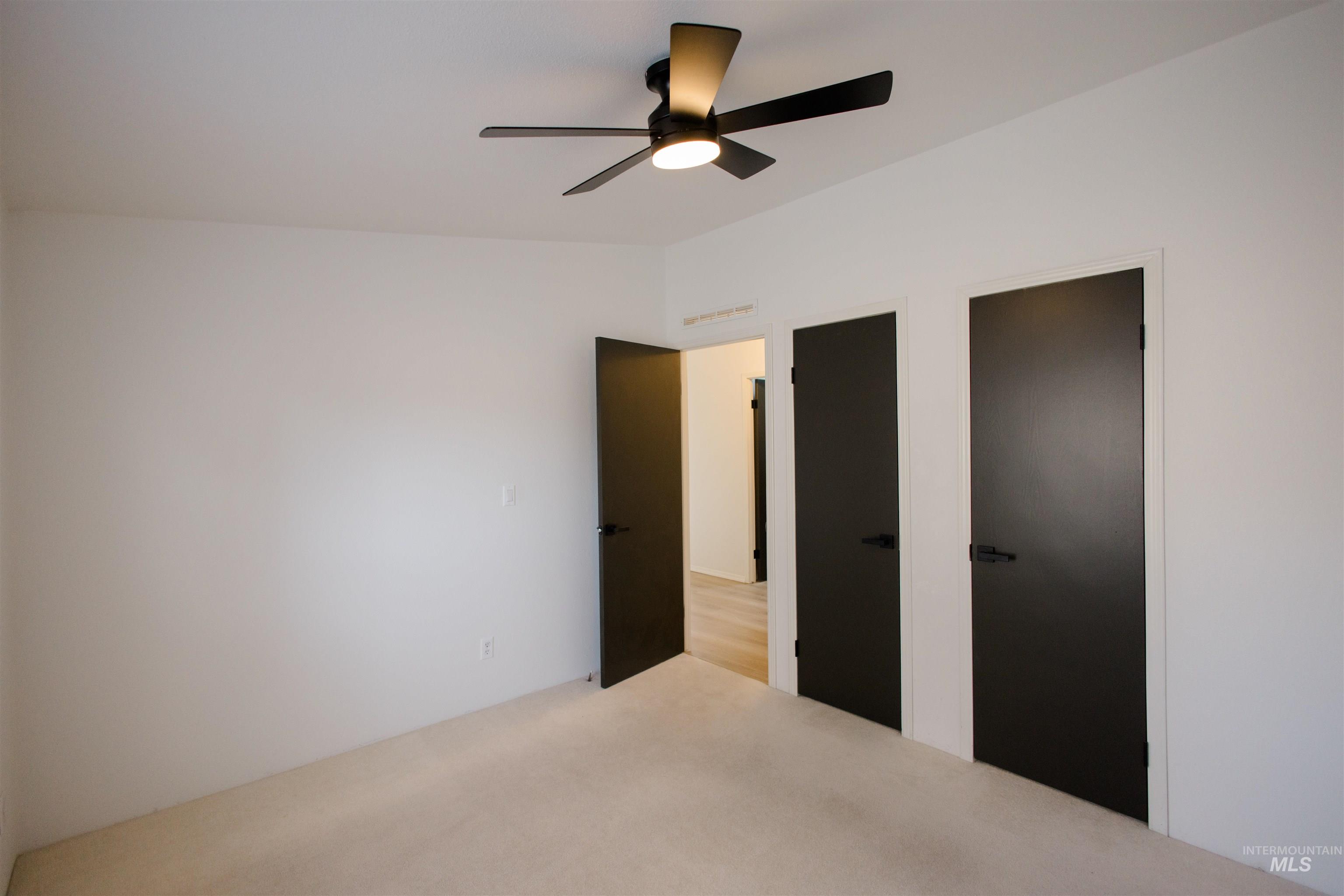 Unfurnished bedroom with ceiling fan, carpet floors, and two closets