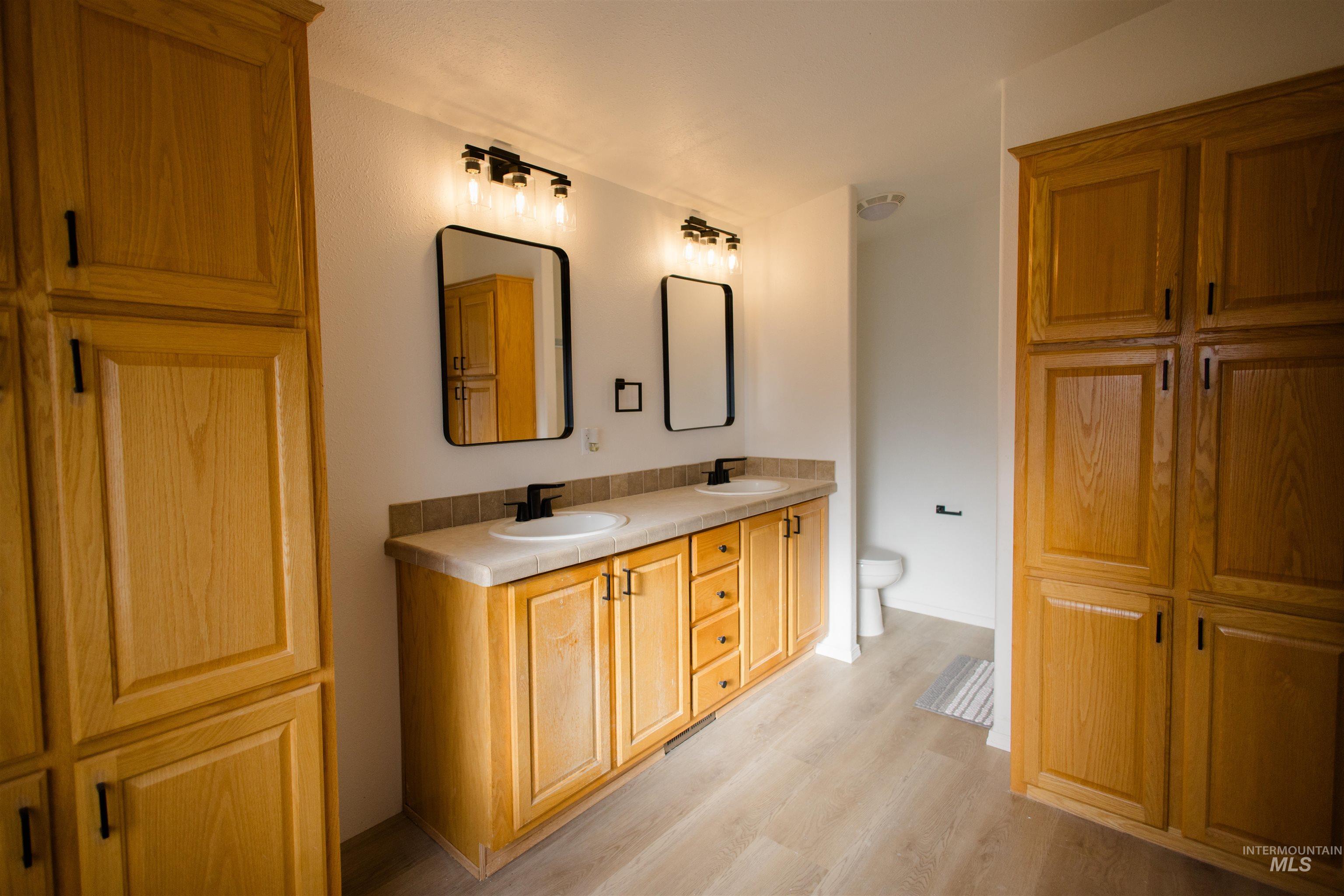 Full bathroom with double vanity and light wood-style flooring