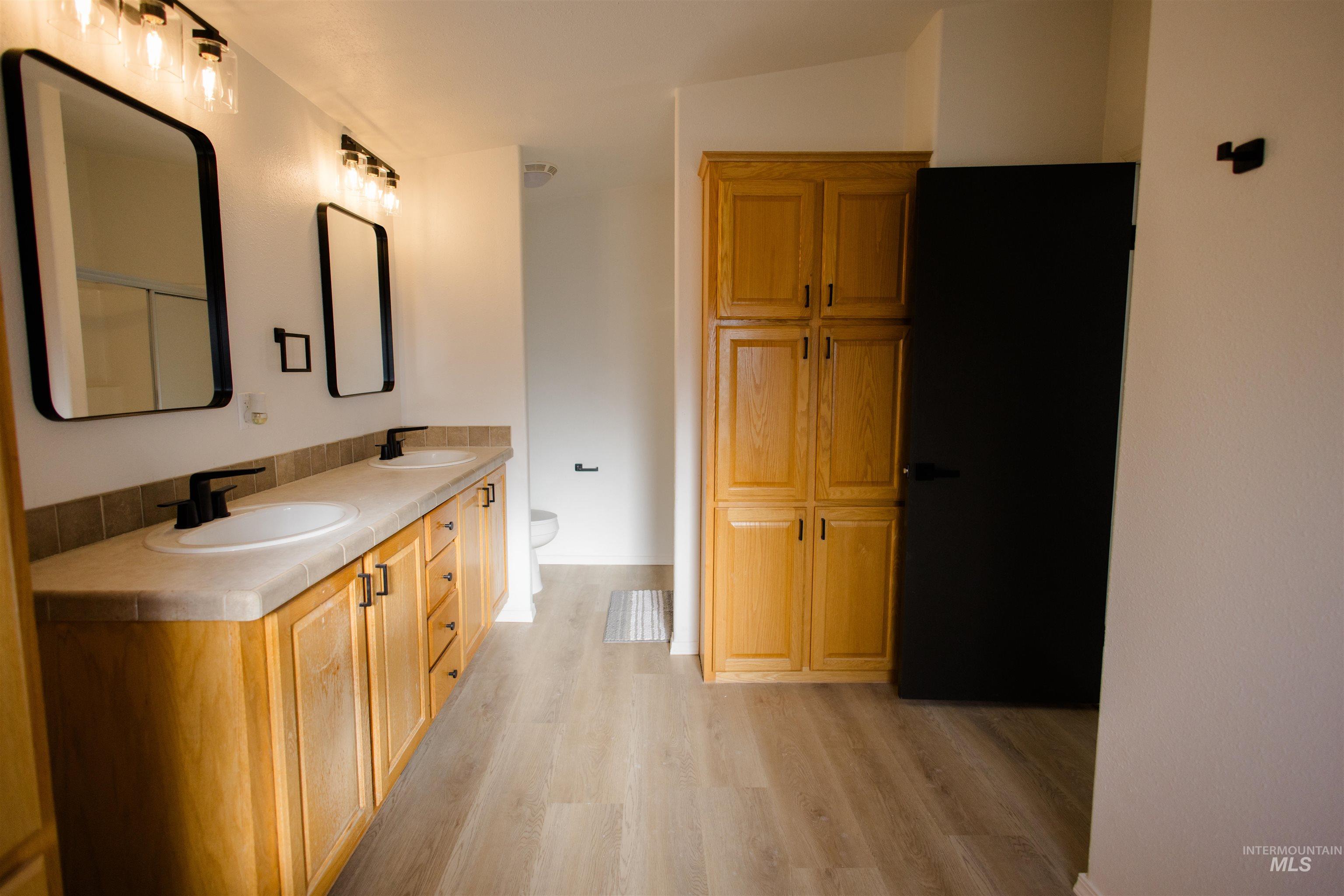 Full bathroom featuring double vanity and light wood-style flooring