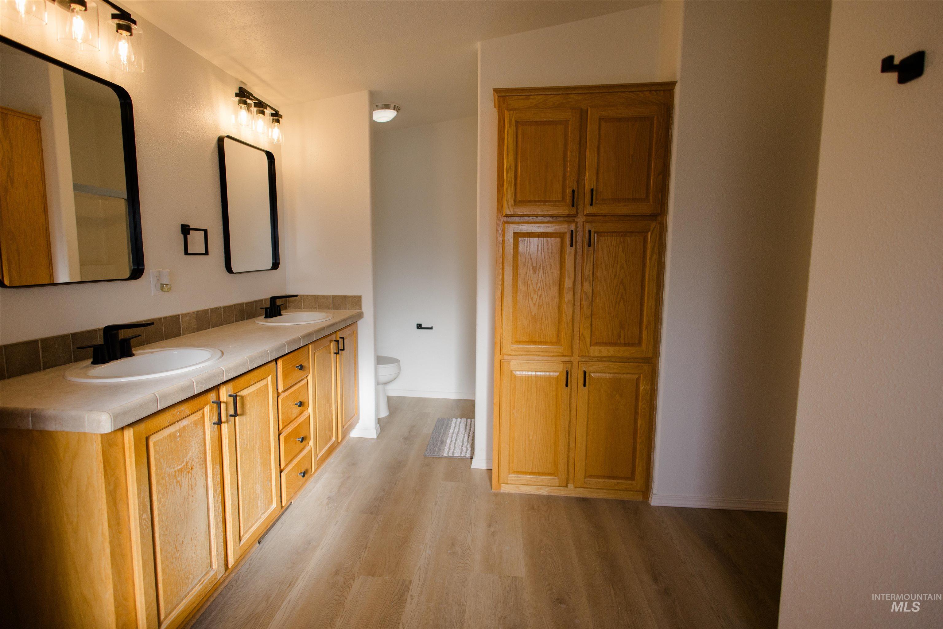 Bathroom featuring double vanity and light wood finished floors