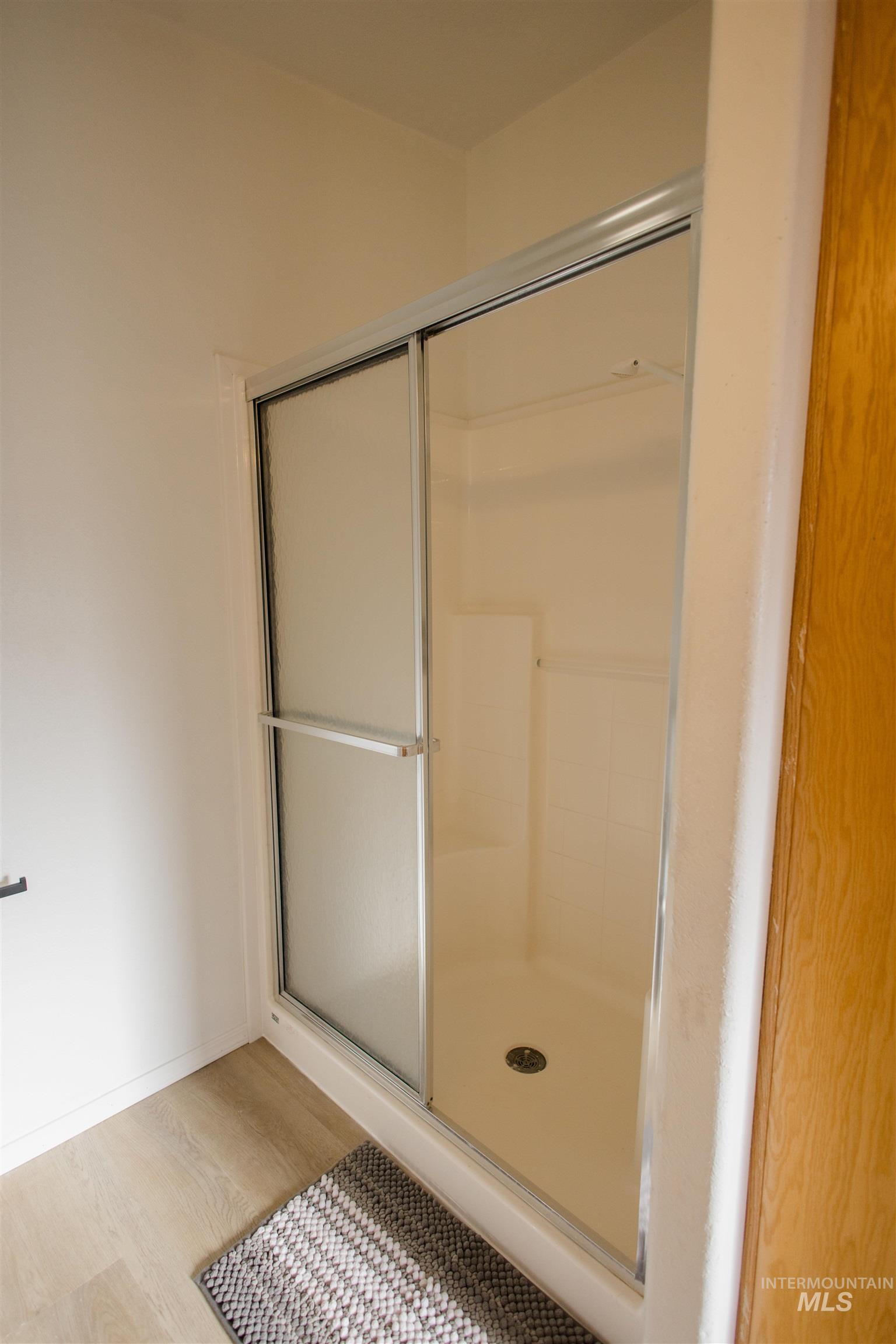 Bathroom featuring a shower stall and light wood finished floors