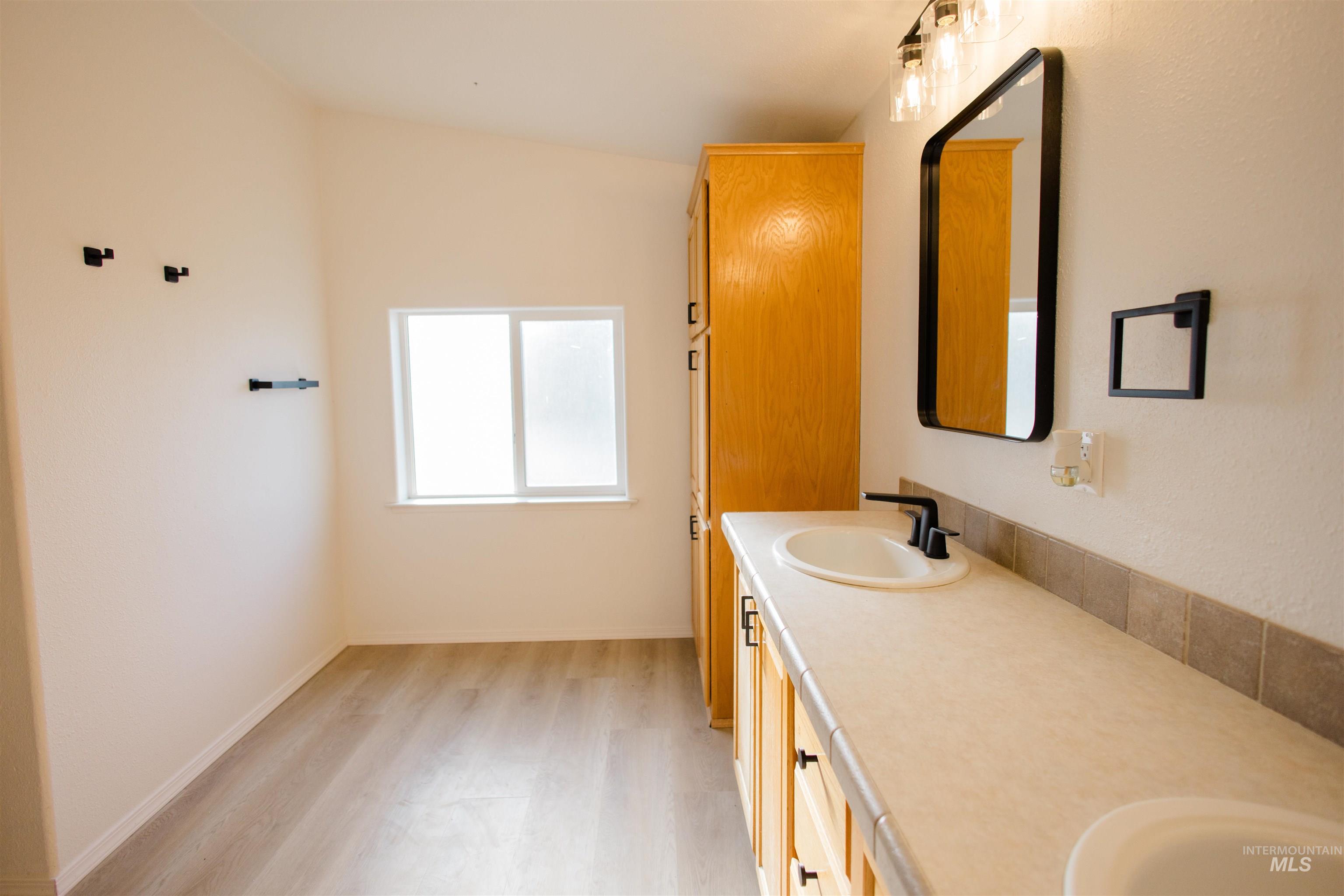 Full bathroom with double vanity and light wood-style flooring