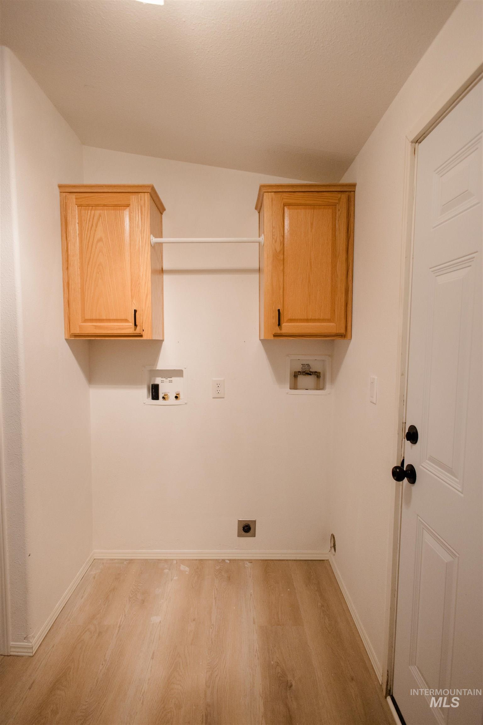 Laundry room featuring hookup for a washing machine, light wood-style floors, cabinet space, and hookup for an electric dryer