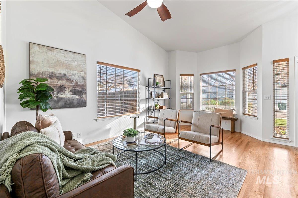 Living area with plenty of natural light, light wood-style floors, and a ceiling fan