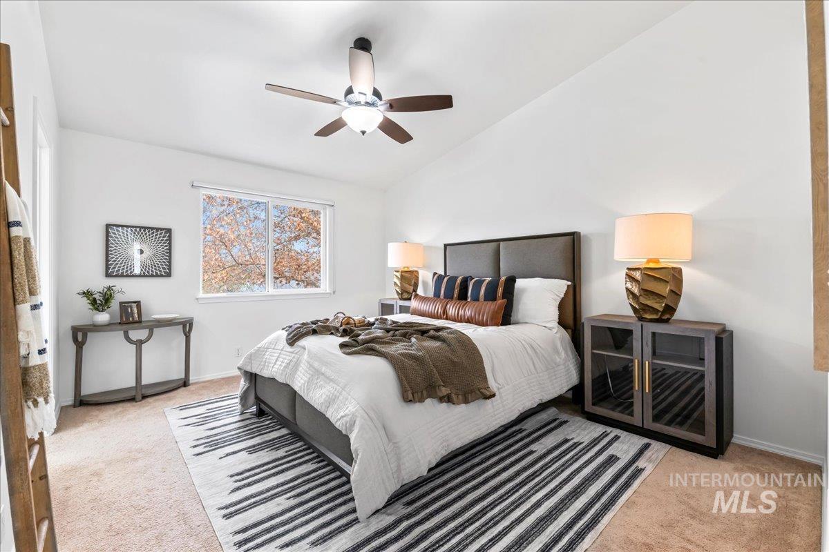Bedroom with lofted ceiling, light carpet, and a ceiling fan