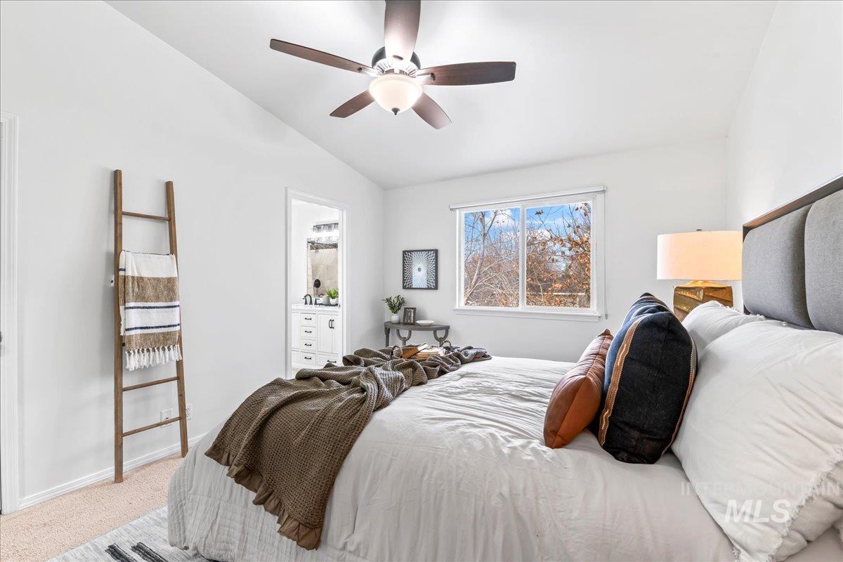 Carpeted bedroom featuring vaulted ceiling and a ceiling fan
