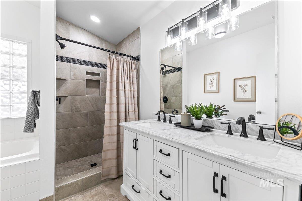 Bathroom featuring a garden tub, double vanity, and tiled shower