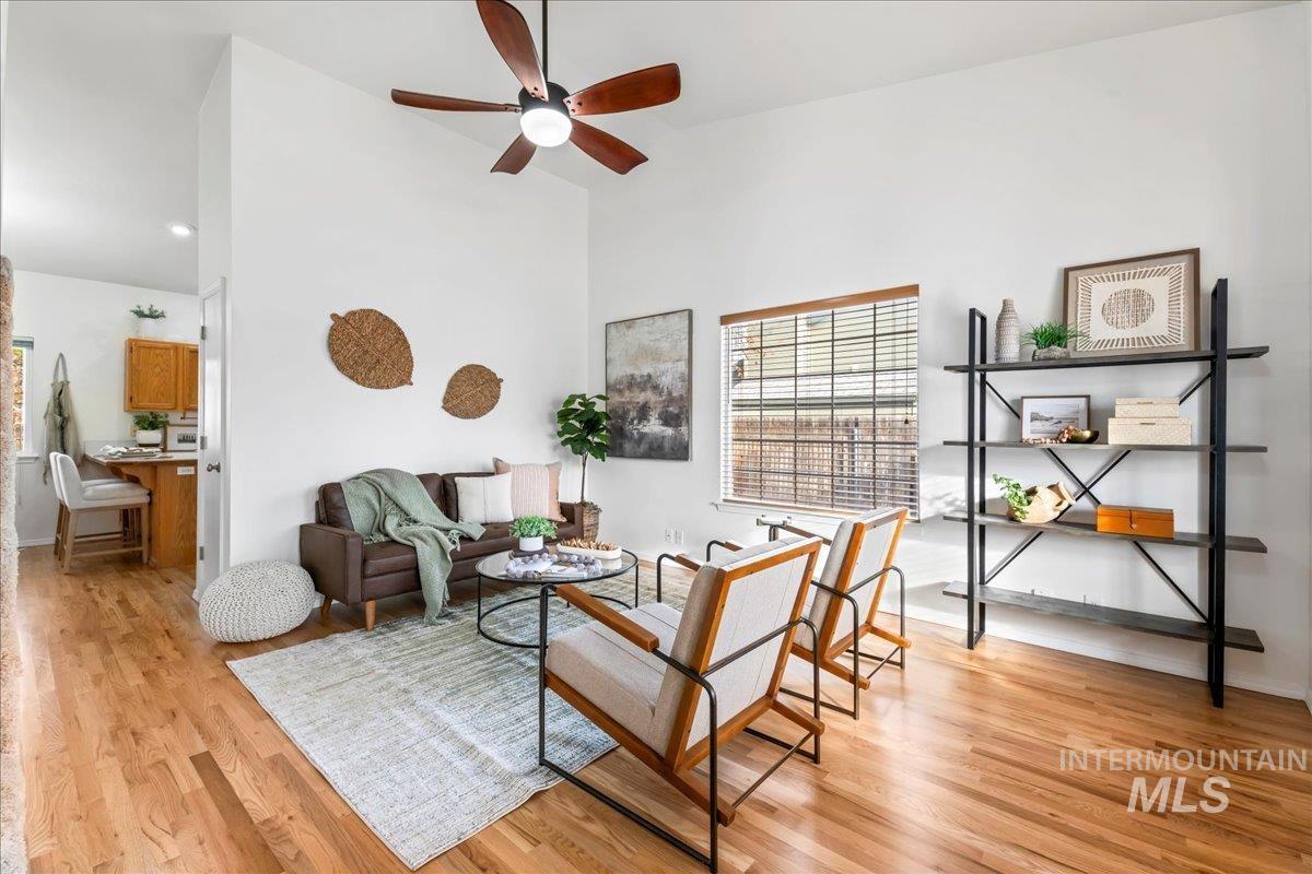Living area featuring ceiling fan, light wood-style flooring, and high vaulted ceiling