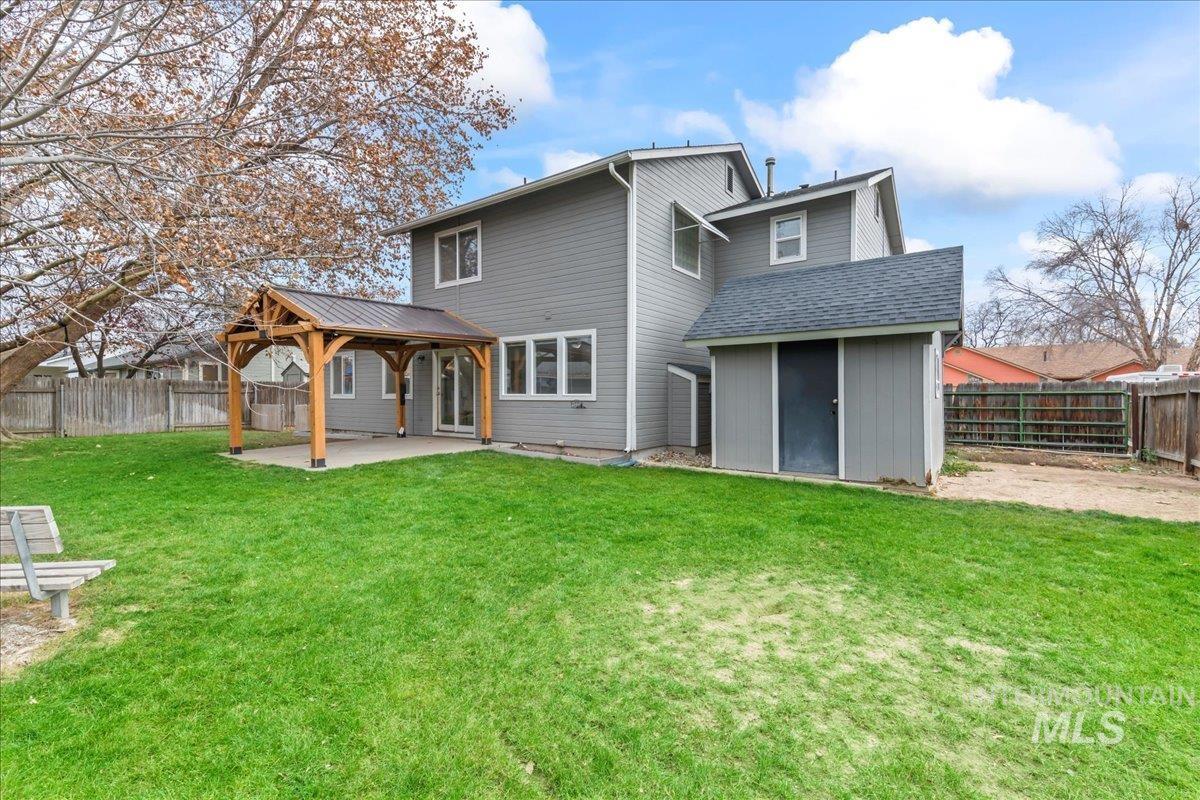 Back of house featuring a patio area, a fenced backyard, a gazebo, and roof with shingles