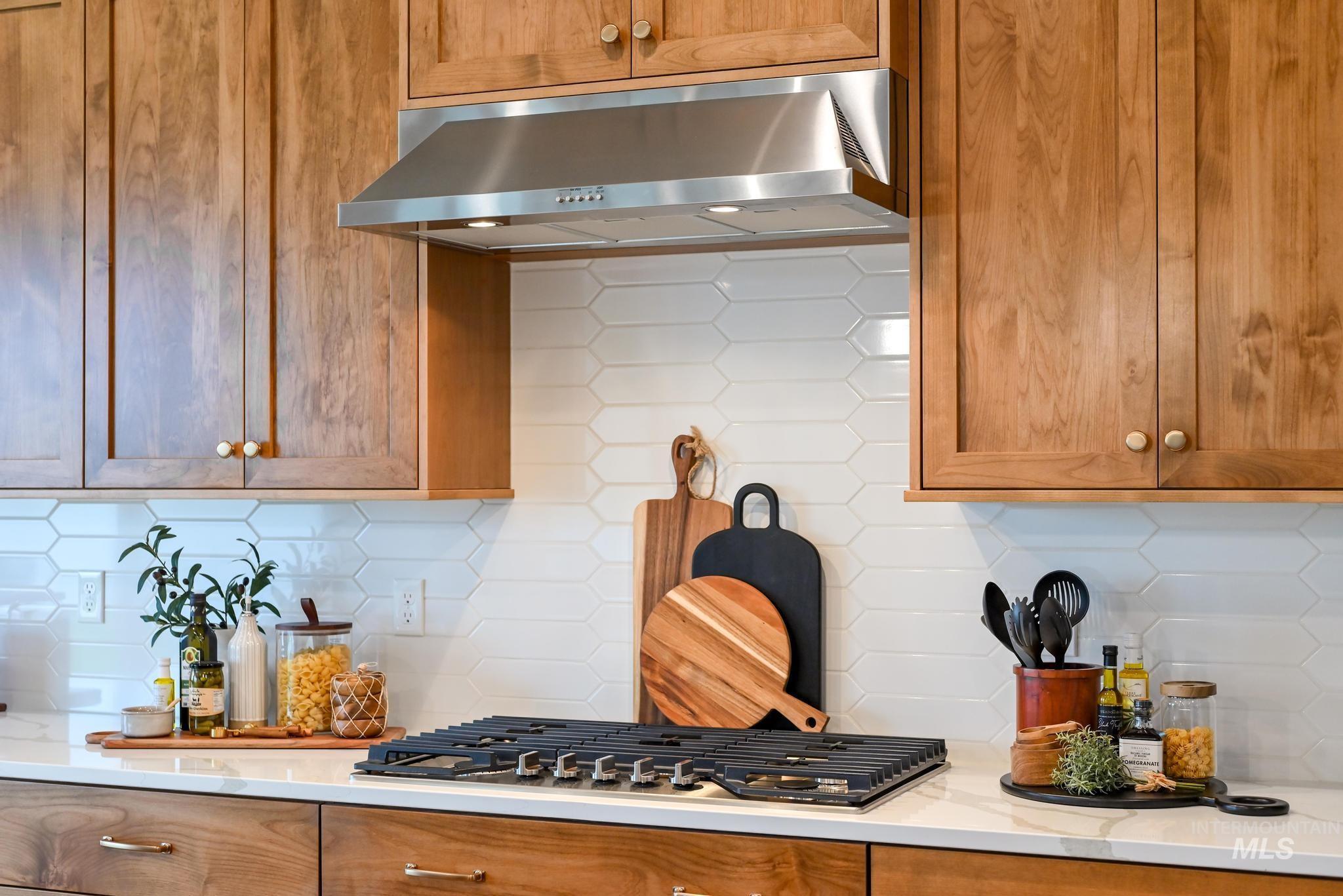 Kitchen featuring tasteful backsplash, brown cabinetry, and under cabinet range hood