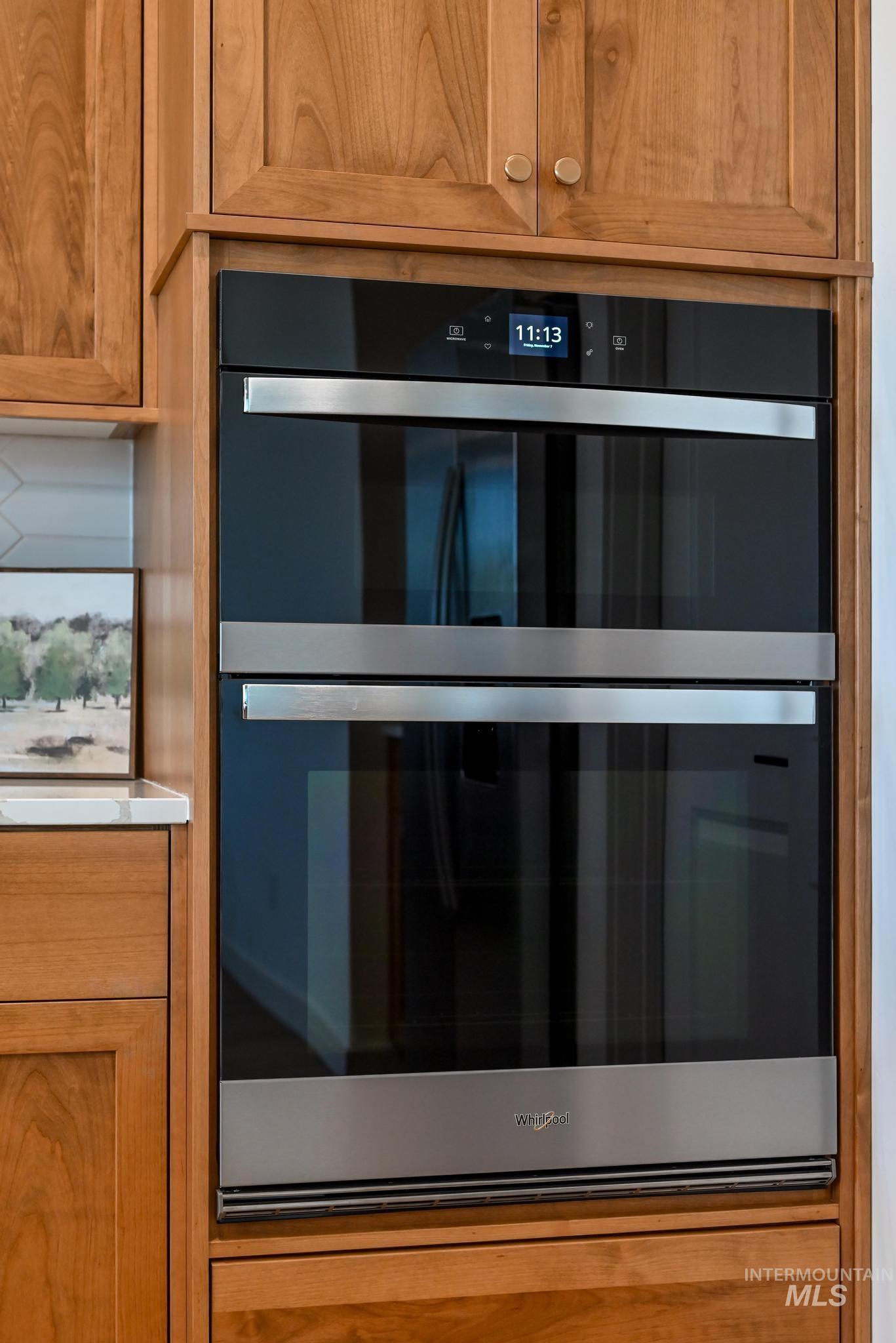Detailed view of brown cabinets, stainless steel double oven, and light countertops