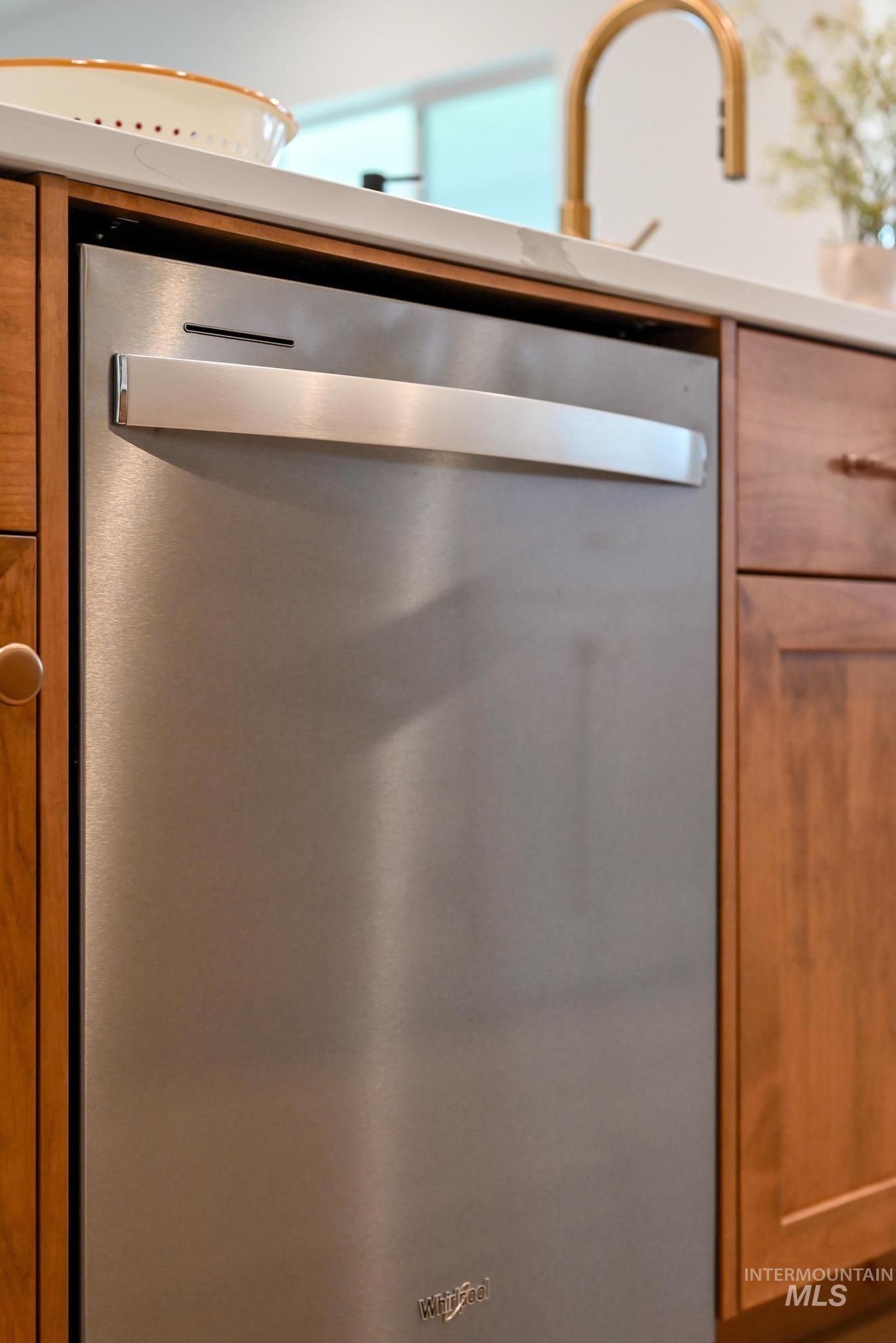 Kitchen view of dishwasher and brown cabinets