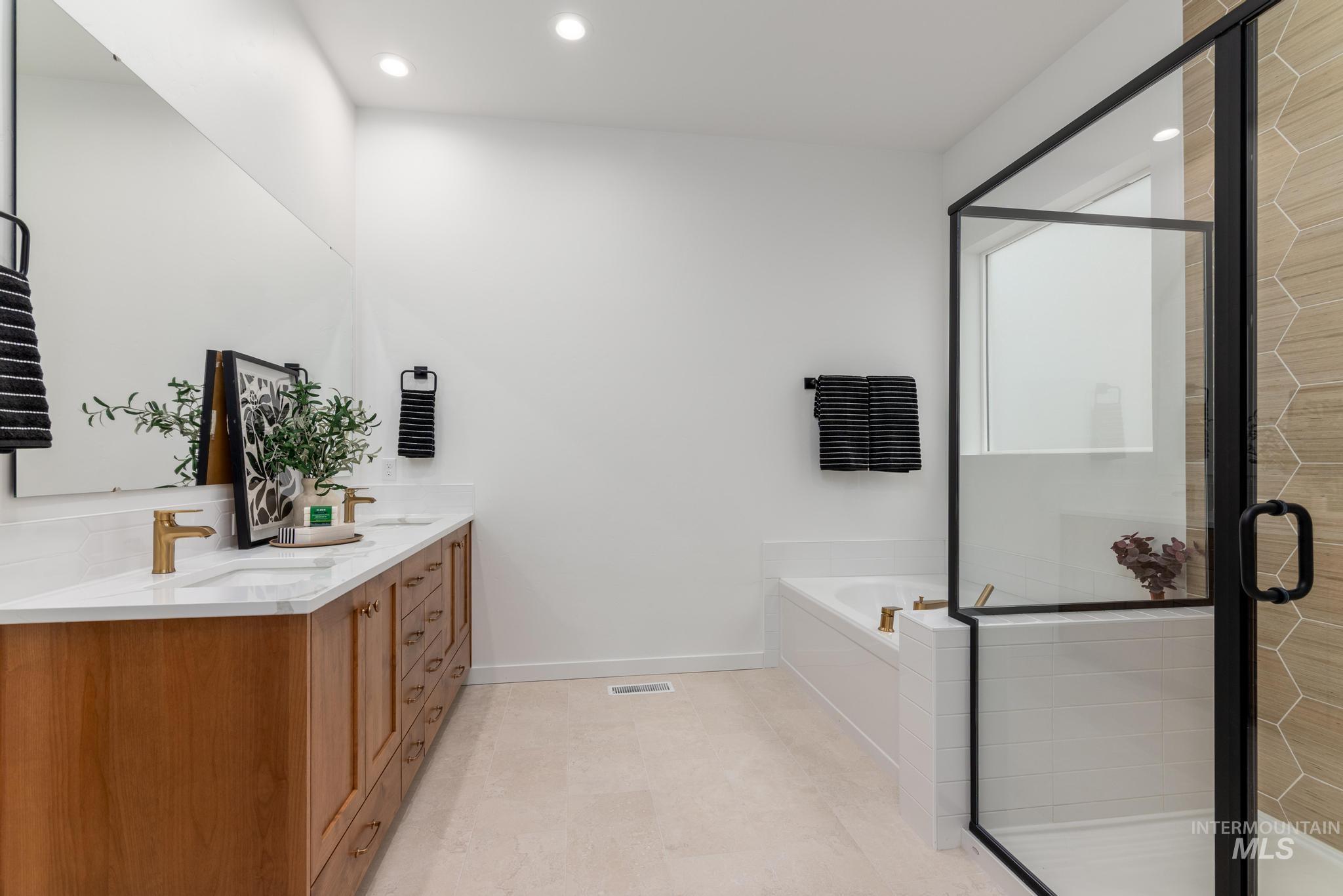 Bathroom with a bath, double vanity, a shower stall, and recessed lighting