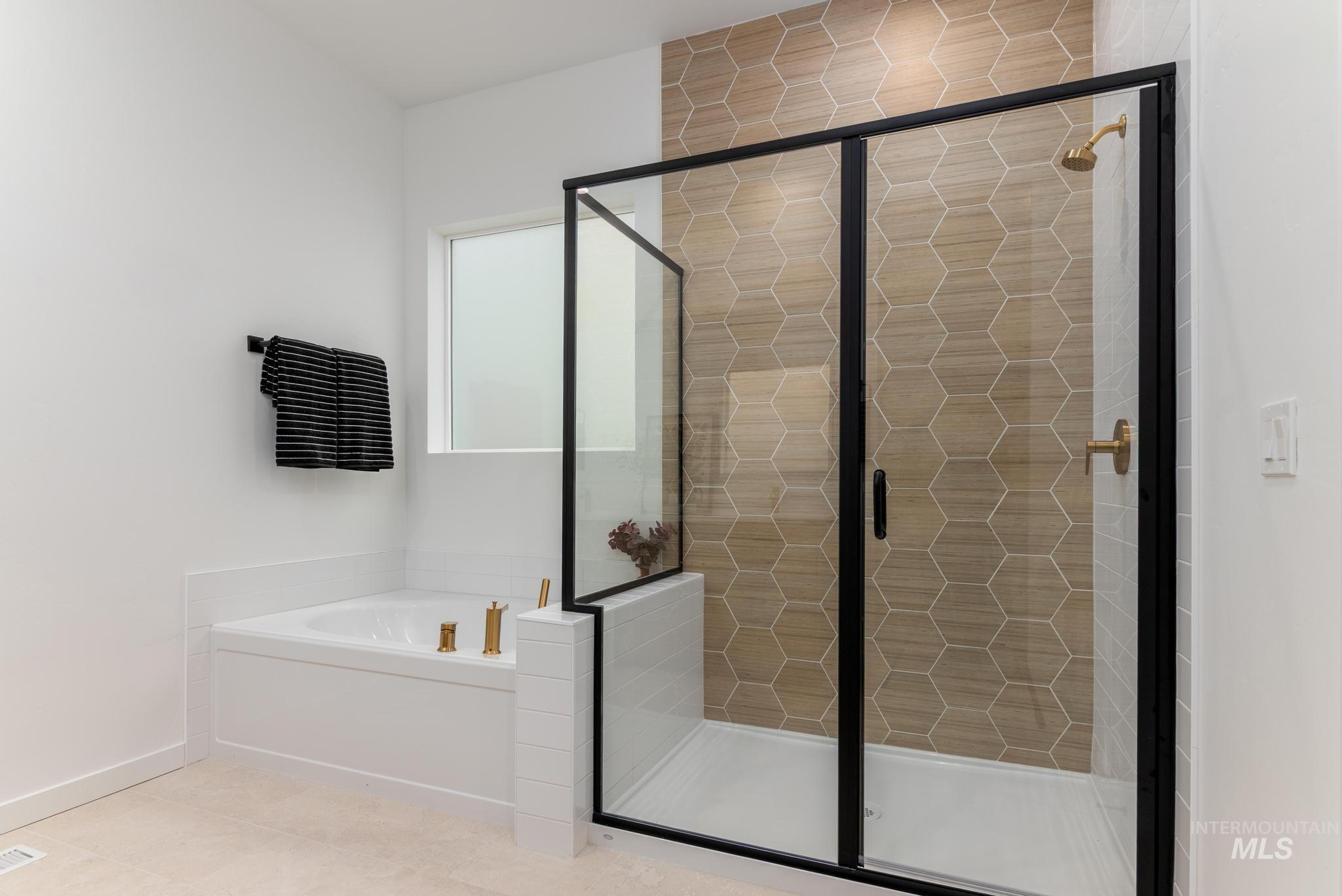 Bathroom featuring a garden tub, a shower stall, and tile patterned floors
